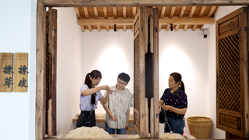 A staff member introduces the Xuan paper-making technique to tourists at an industrial park in Jingxian County, Xuancheng City, east China's Anhui Province, June 24, 2025. /VCG