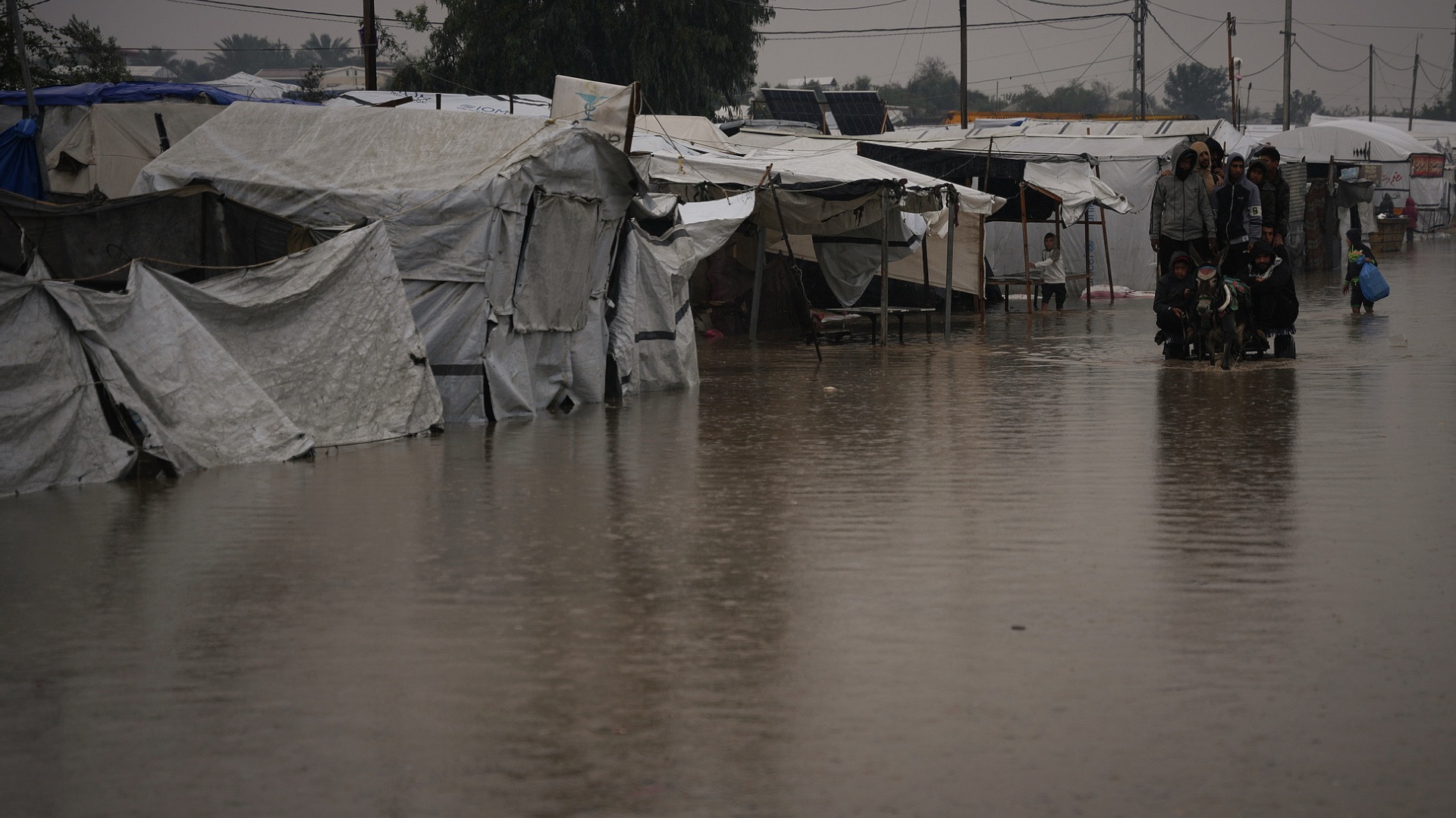 Palestinians cross a flooded street following heavy rain in Khan Younis, southern Gaza Strip, December 11, 2025. /VCG