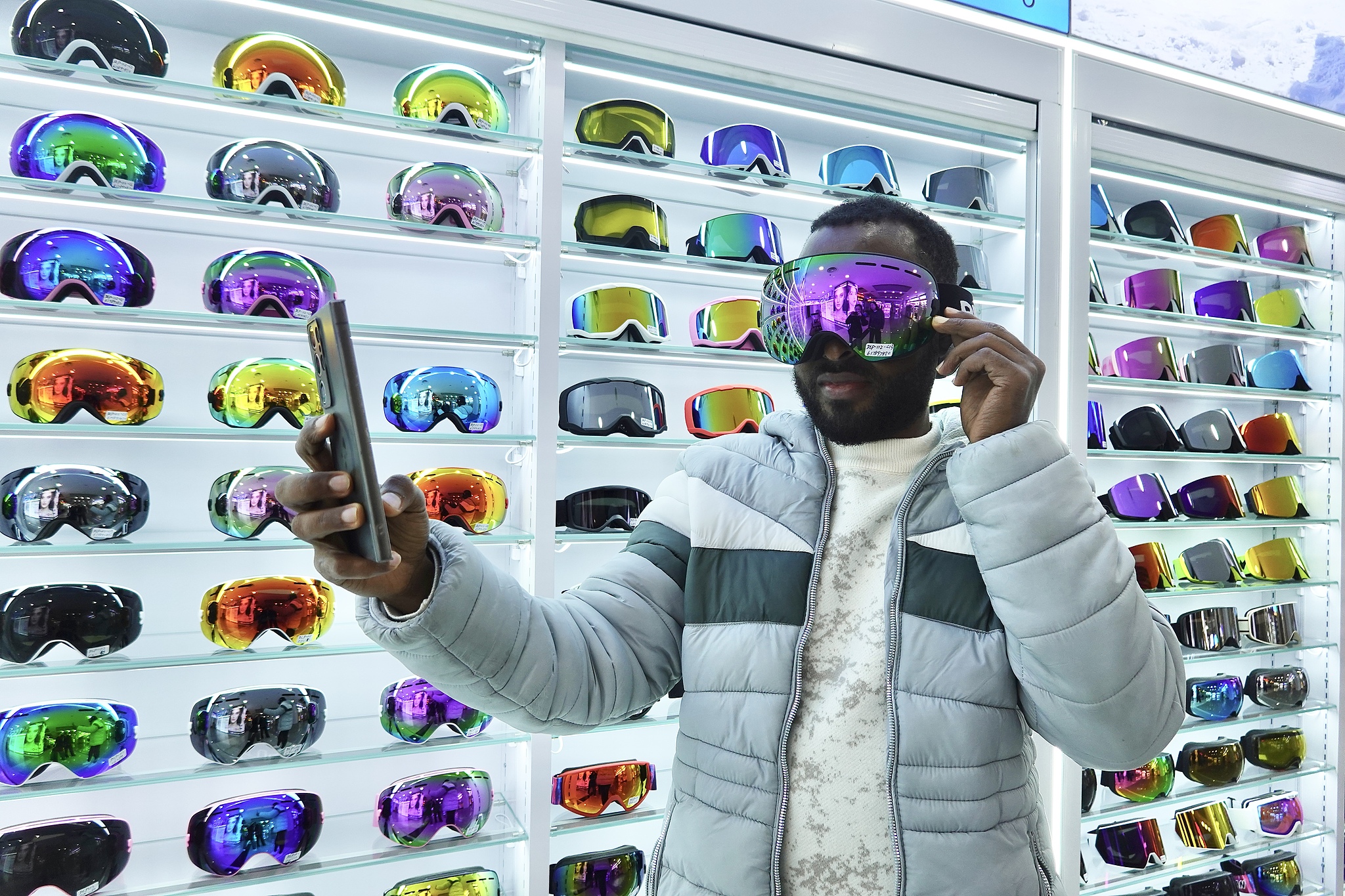 A foreign buyer tries on a pair of ski goggles at the Yiwu International Trade Market in east China's Zhejiang Province on December 13, 2025. /VCG