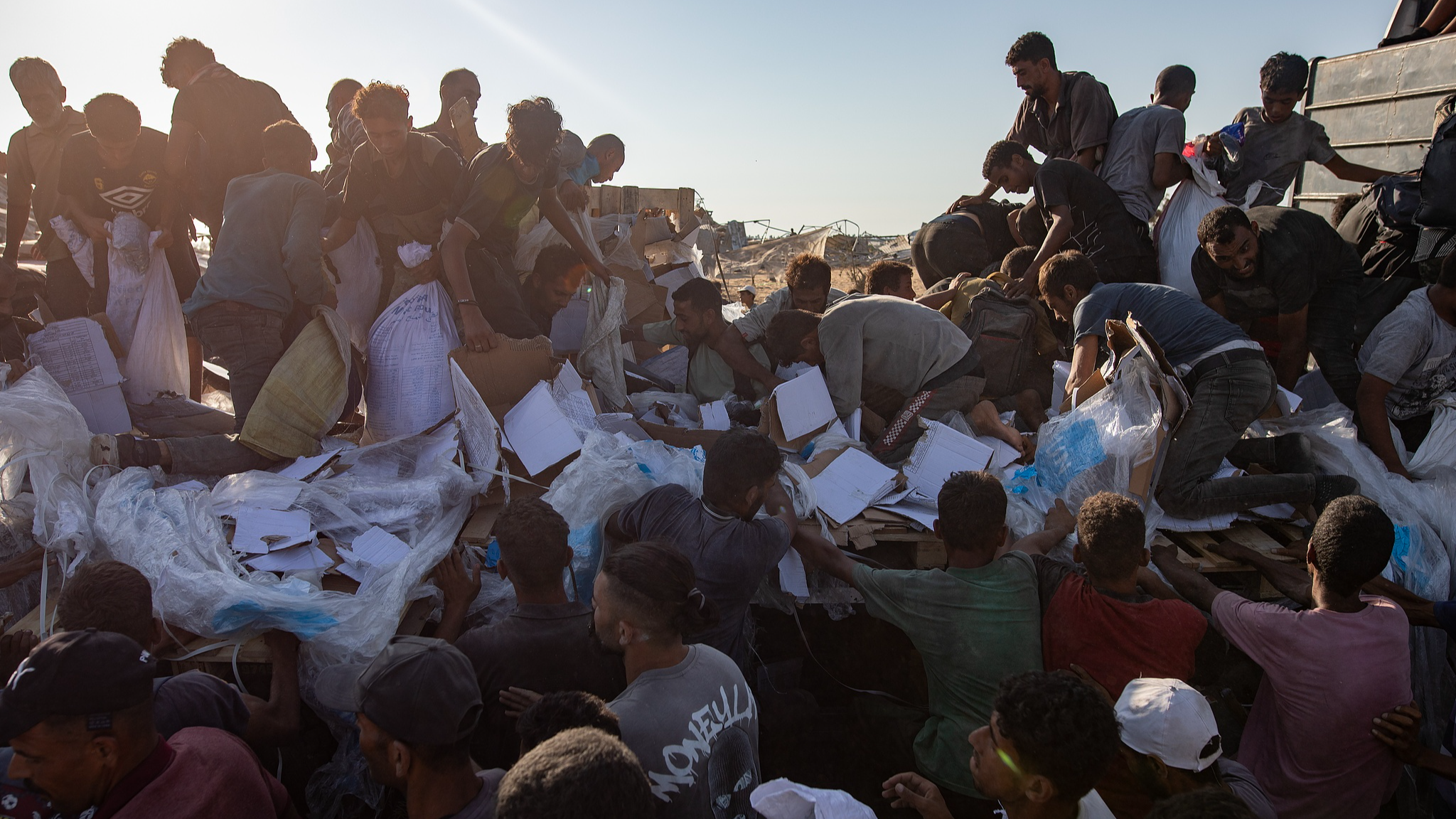 Internally displaced Palestinians climb aid trucks to get food near a food distribution point in the Morag corridor, south of Khan Younis, in the southern Gaza Strip, August 4, 2025. /VCG