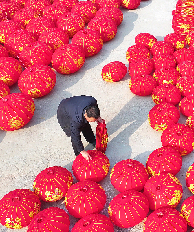 A worker arranges rows of freshly-made red lanterns at a workshop in a village in Shanxi Province, December 10, 2025. /VCG