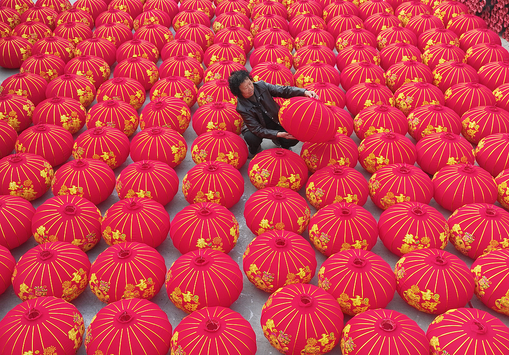 A worker arranges rows of freshly-made red lanterns at a workshop in a village in Shanxi Province, December 10, 2025. /VCG