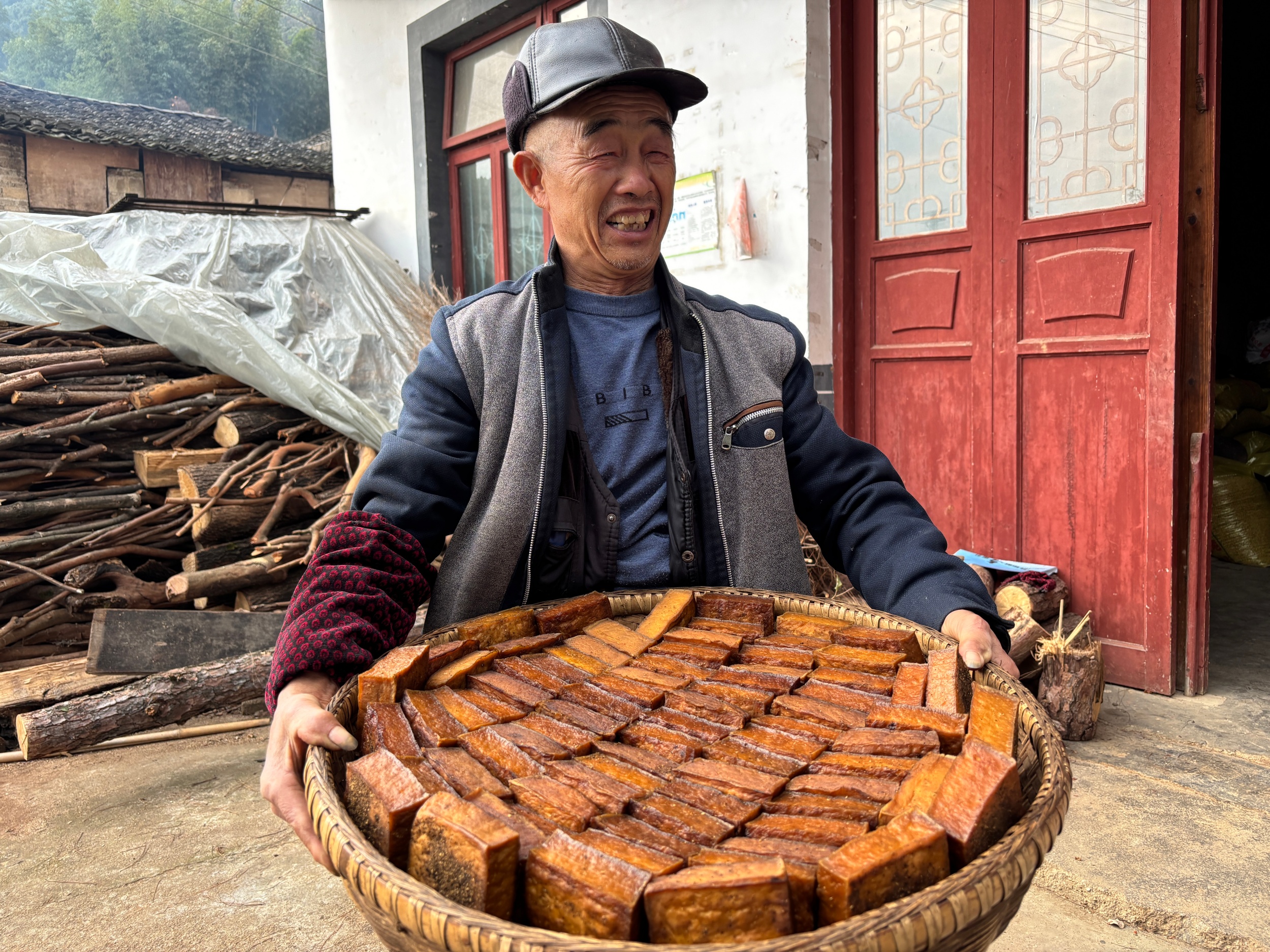 A villager holds a basket of traditional smoked tofu in Laozhai Village, Yuping Dong Autonomous County, southwest China's Guizhou Province, on December 17, 2025. /Tongren Media Convergence Center