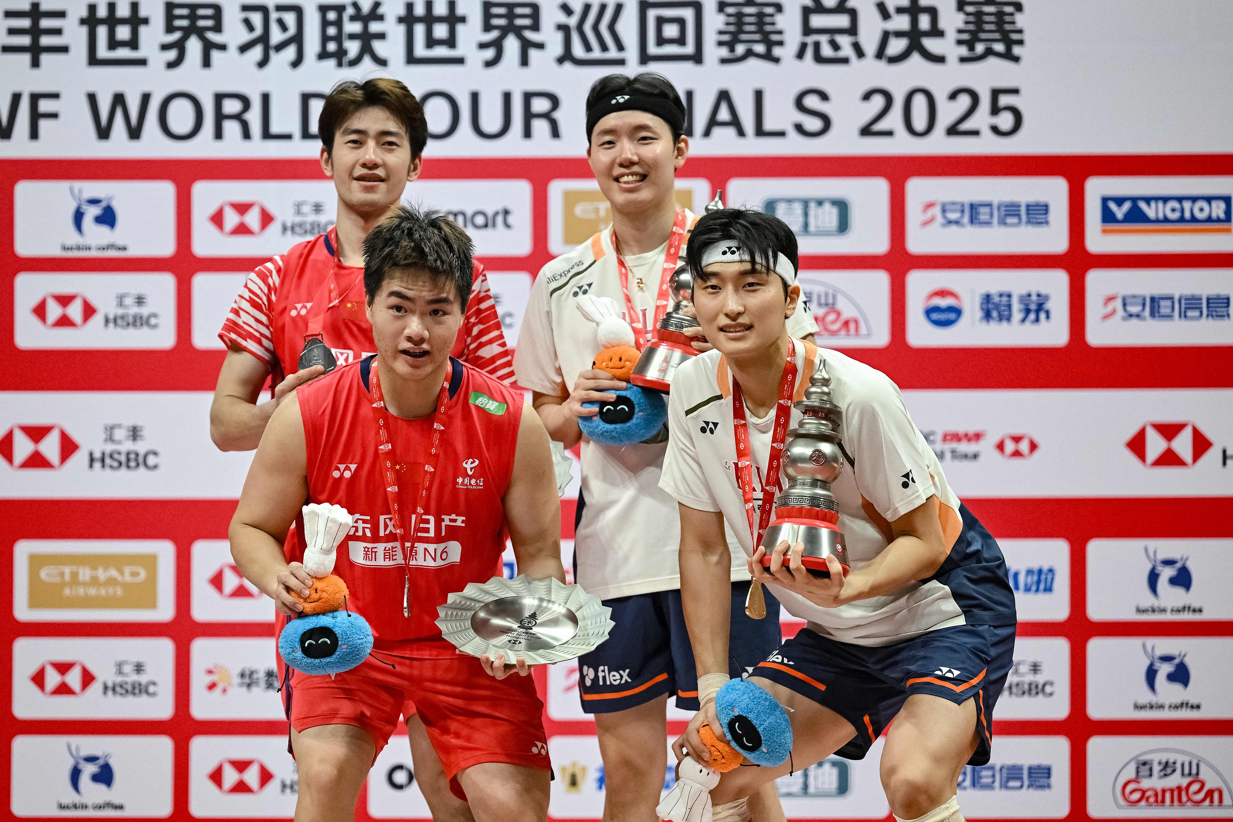 Gold medalists Seo Seung-jae (back R) and Kim Won-ho (front R) from the Republic of Korea display their awards alongside silver medalists Wang Chang (back L) and Liang Weikeng (front L) of China after the men's doubles final at the BWF World Tour Finals in Hangzhou, China, December 21, 2025. /VCG