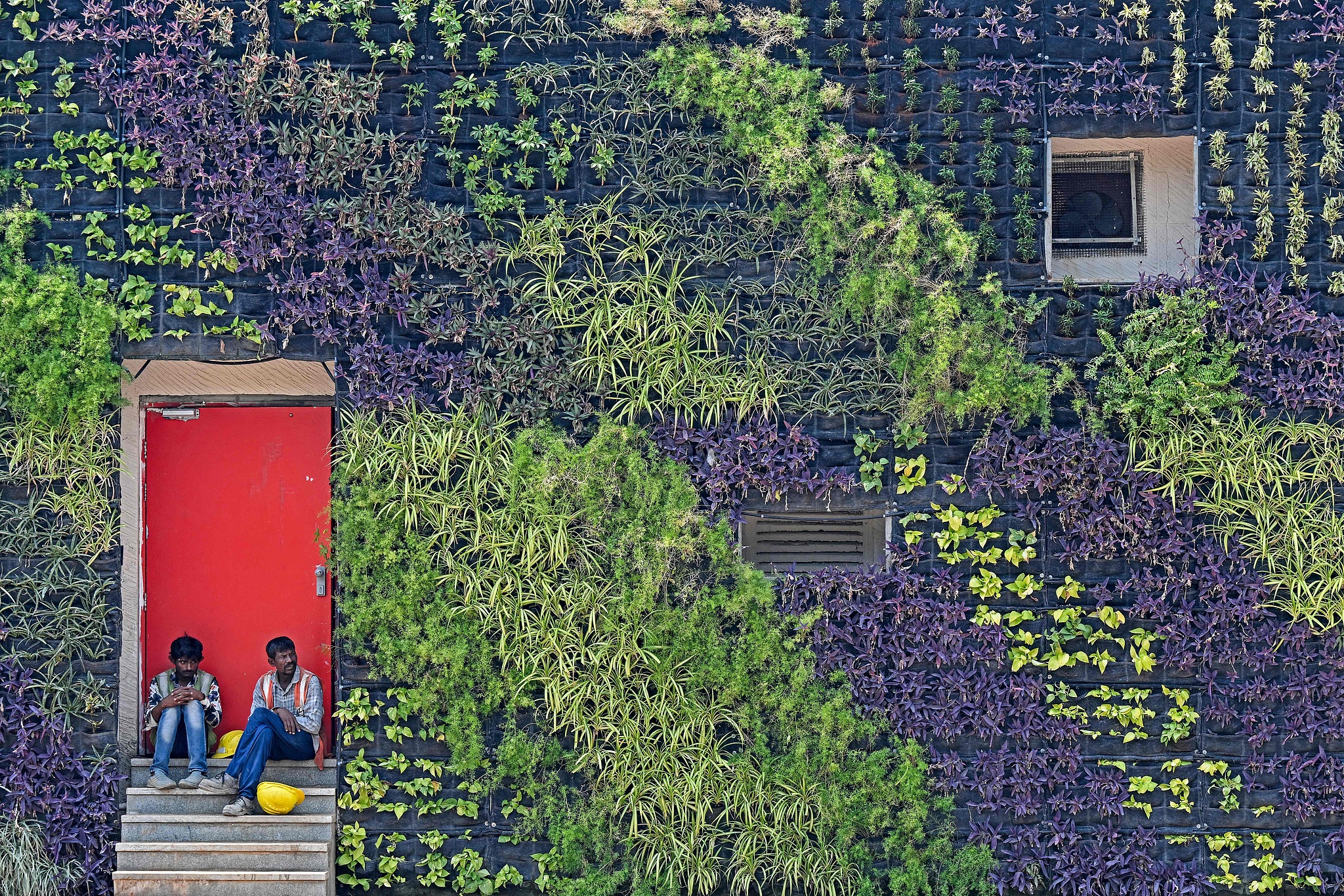 Laborers take shade in front of the facade of a building decorated with plants on a hot summer day in Mumbai, India, April 8, 2025. /VCG
