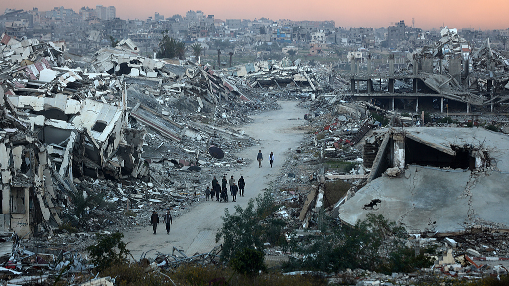 People walk on a road flanked by destroyed houses in the Nuseirat camp in the central Gaza Strip, December 26, 2025. /VCG