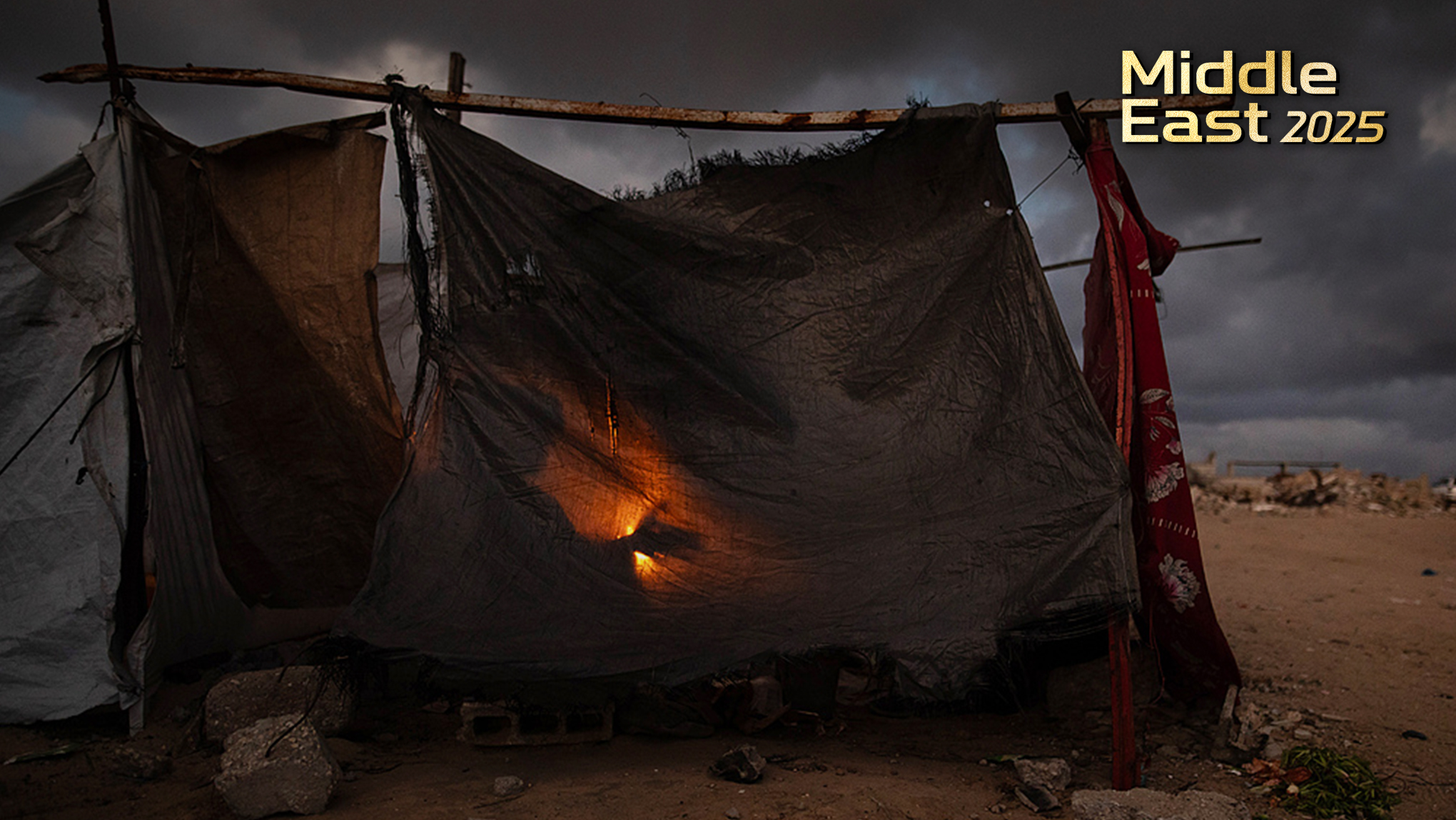 Members of a displaced Palestinian family warm themselves around a fire outside their shelter in the city of Khan Younis, southern Gaza Strip, December 27, 2025. /VCG