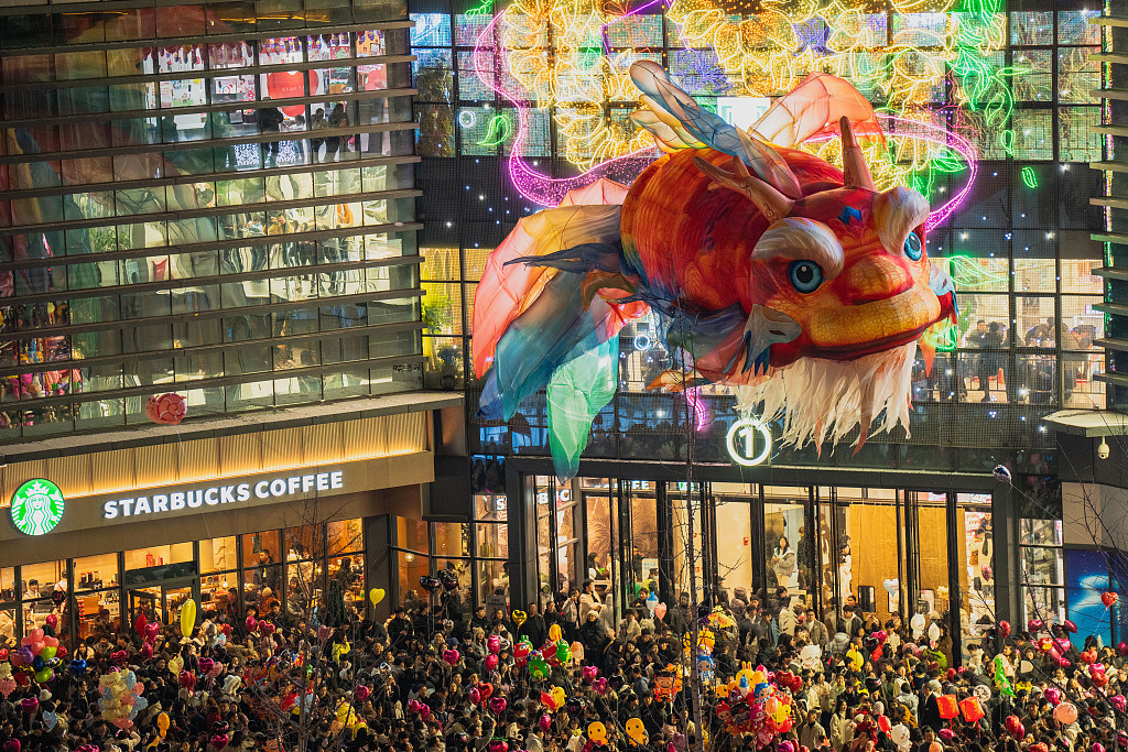 Thousands of people watch the performance of a giant floating Aoyu fish lantern at the plaza of a commercial complex in Enshi, central China's Hubei Province, on December 31, 2025. /VCG