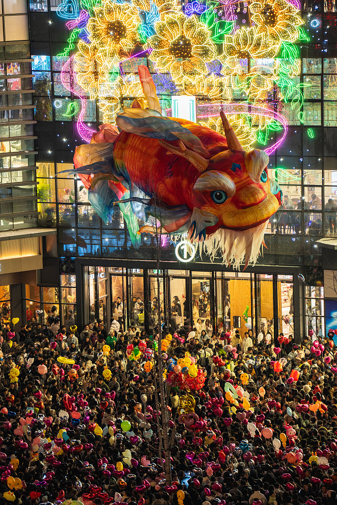 Thousands of people watch the performance of a giant floating Aoyu fish lantern at the plaza of a commercial complex in Enshi, central China's Hubei Province, on December 31, 2025. /VCG