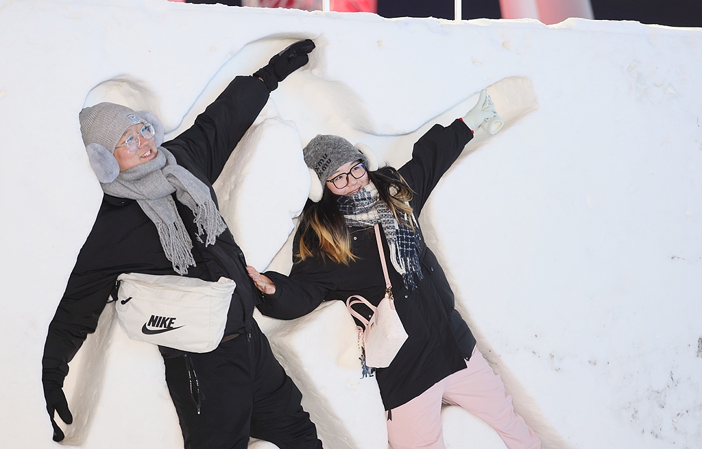 Visitors squeeze into thick snow walls to snap fun photos at Harbin Ice and Snow World on December 31, 2025. /VCG