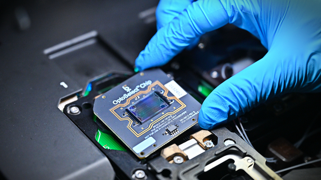 A staff member places a chip used for cell screening into a single-cell optoelectronic screening system in Hefei, Anhui Province, China, October 17, 2025. /VCG