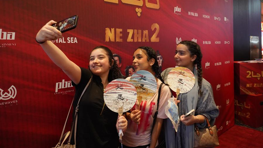 Young cinemagoers take a selfie in front of a promotional display for the premiere of Chinese animated blockbuster 