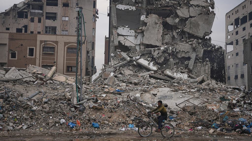 A Palestinian man rides a bicycle past destroyed buildings in Gaza, January 4, 2026. /VCG