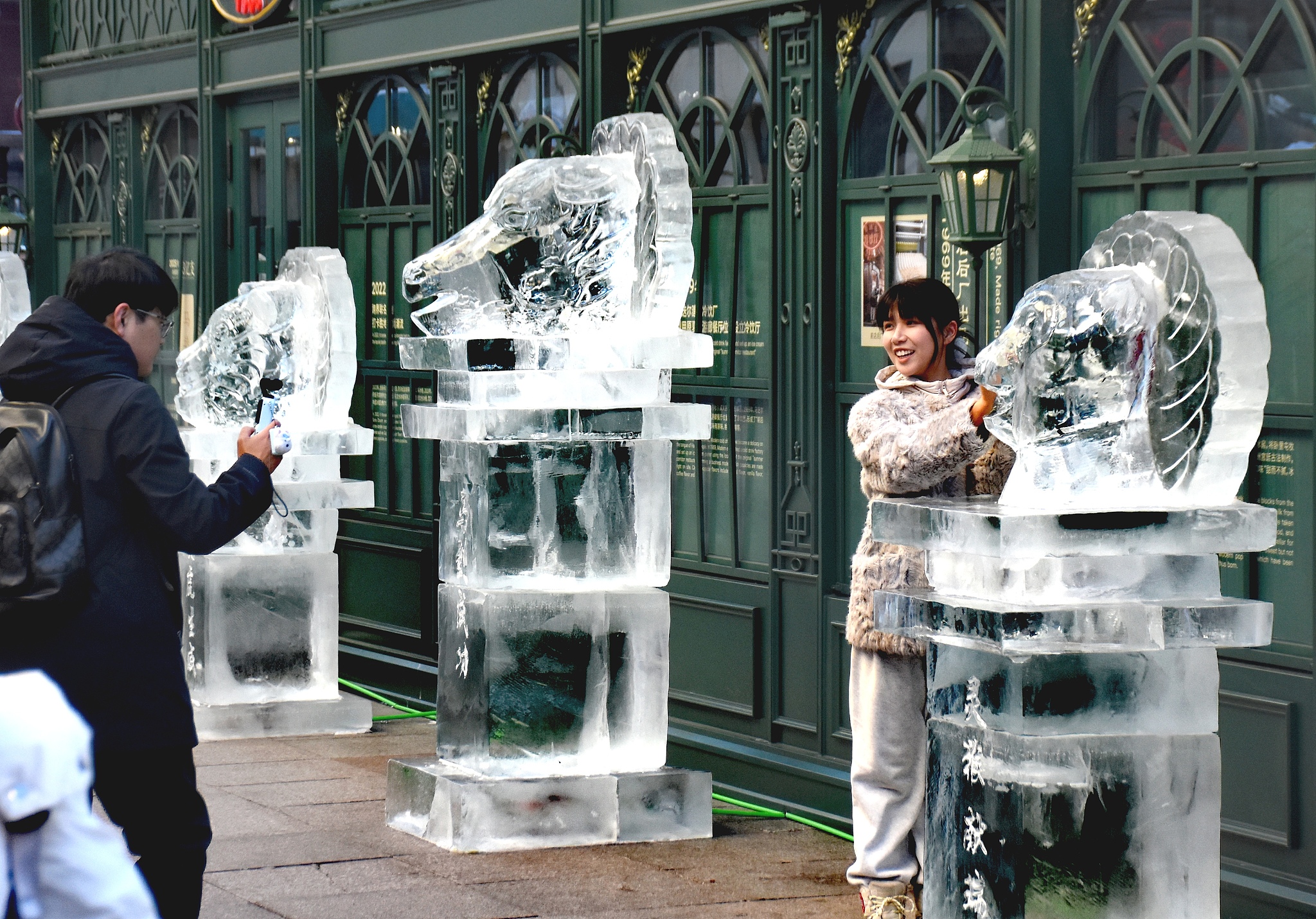 A visitor poses for photos with one of the Chinese zodiac-themed ice sculptures in Harbin, Heilongjiang Province on January 4, 2026. /VCG