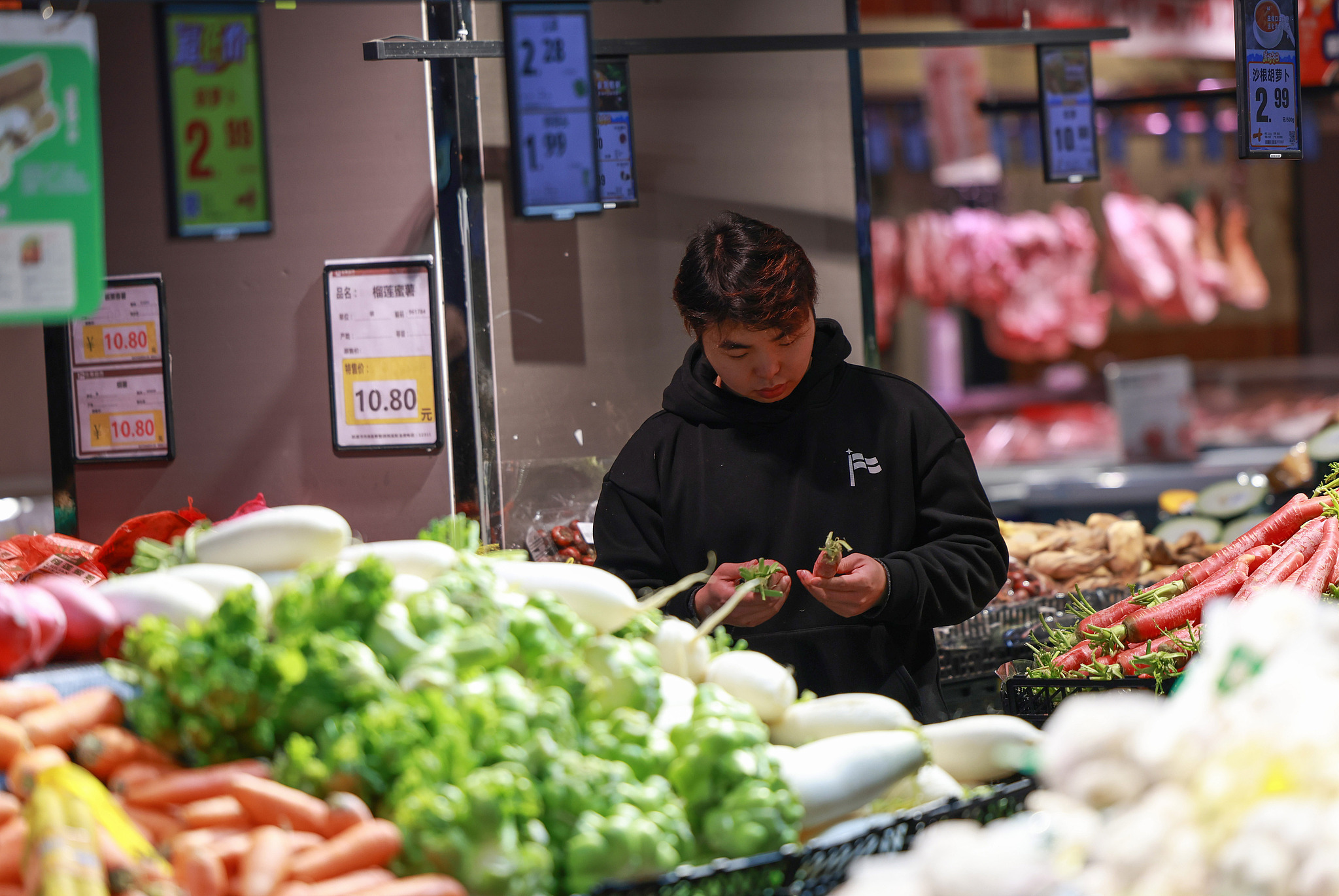A customer choosing vegetables in a supermarket in Kaili, Guizhou Province, China, Jan 9, 2026. /VCG