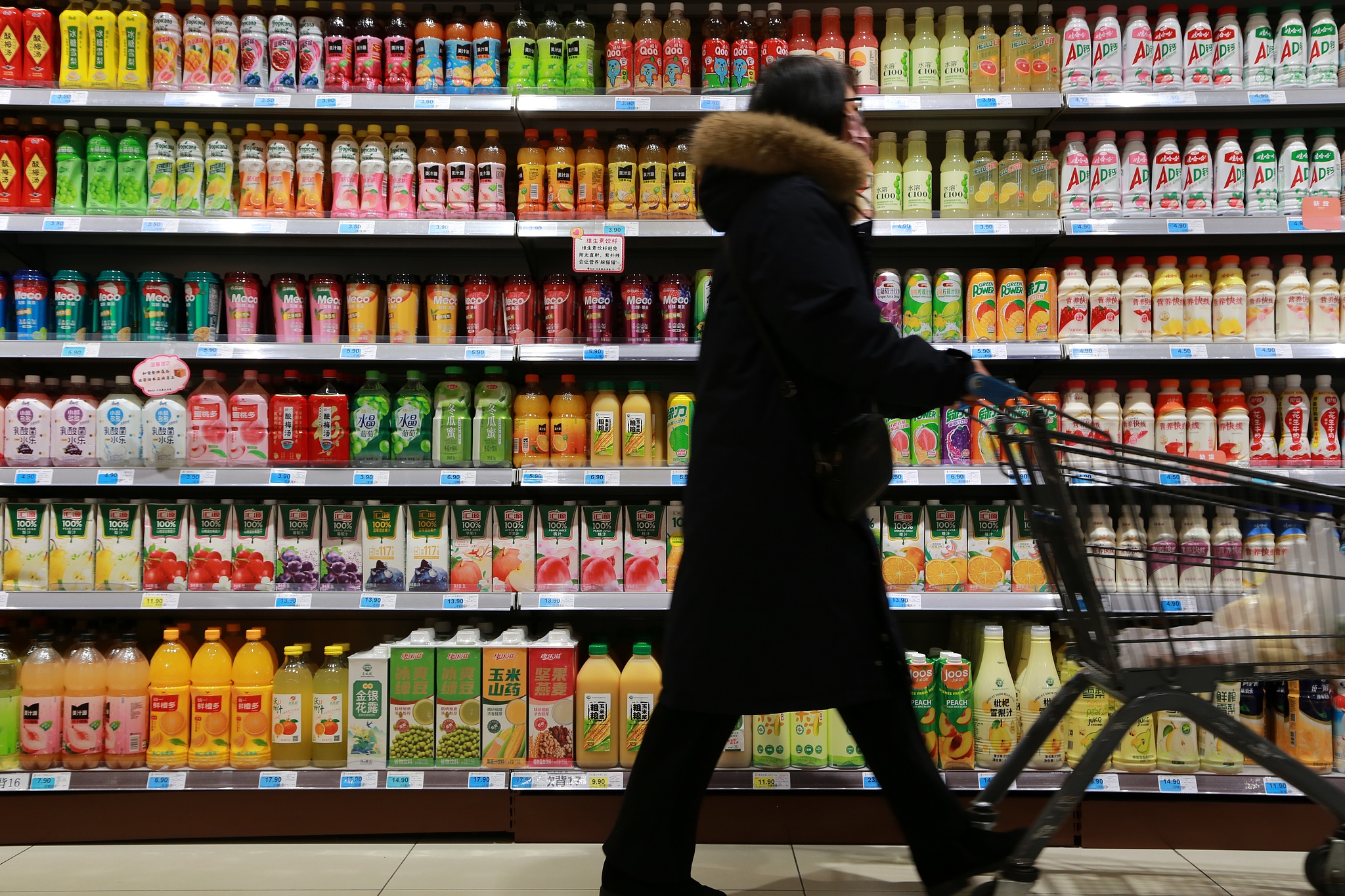 A consumer pushing a shopping trolley along the beverages aisle of a supermarket in Mengzi, Yunnan Province, China, Jan 9, 2026. /VCG