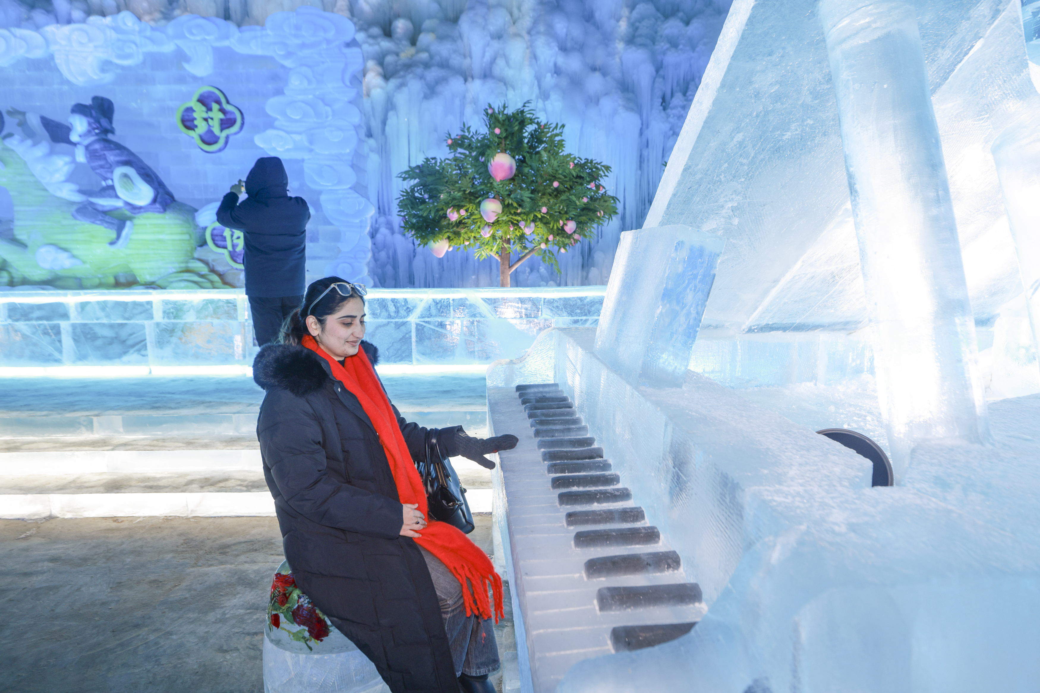 A woman plays an ice piano installation at the 40th Longqing Gorge Ice Lantern Art Festival in Beijing on January 15, 2026. /IC