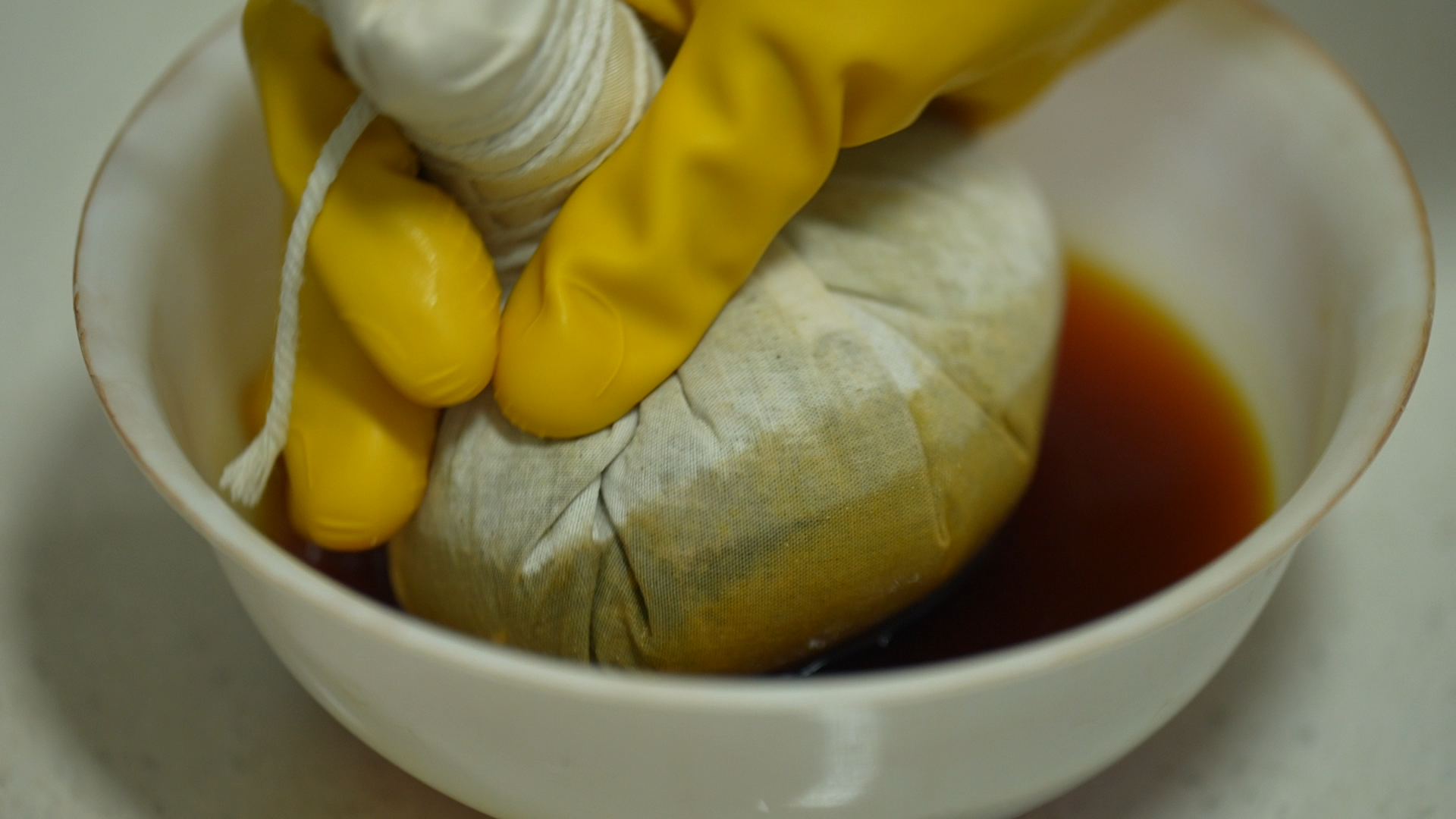 After steaming, a herbal bag is dipped into the medicinal liquid before applying tuoca therapy, Xishuangbanna Dai Autonomous Prefecture, Yunnan Province, southwest China, December 7, 2025. /CGTN