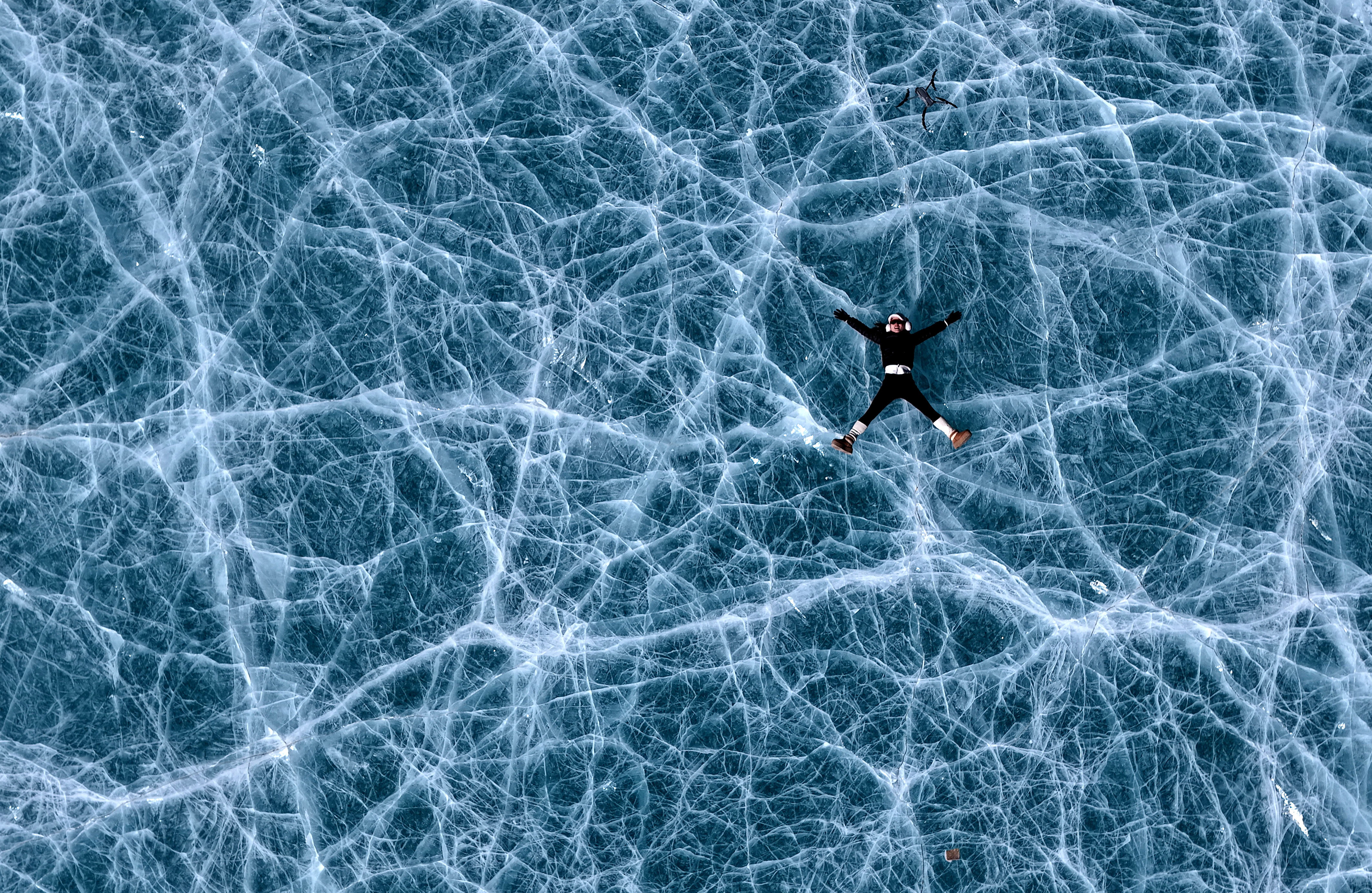 A visitor poses for photos on a frozen alpine lake at the foot of Qiongmu Gonga, a snow-capped mountain in Lhasa, Xizang Autonomous Region on January 16, 2025. /IC