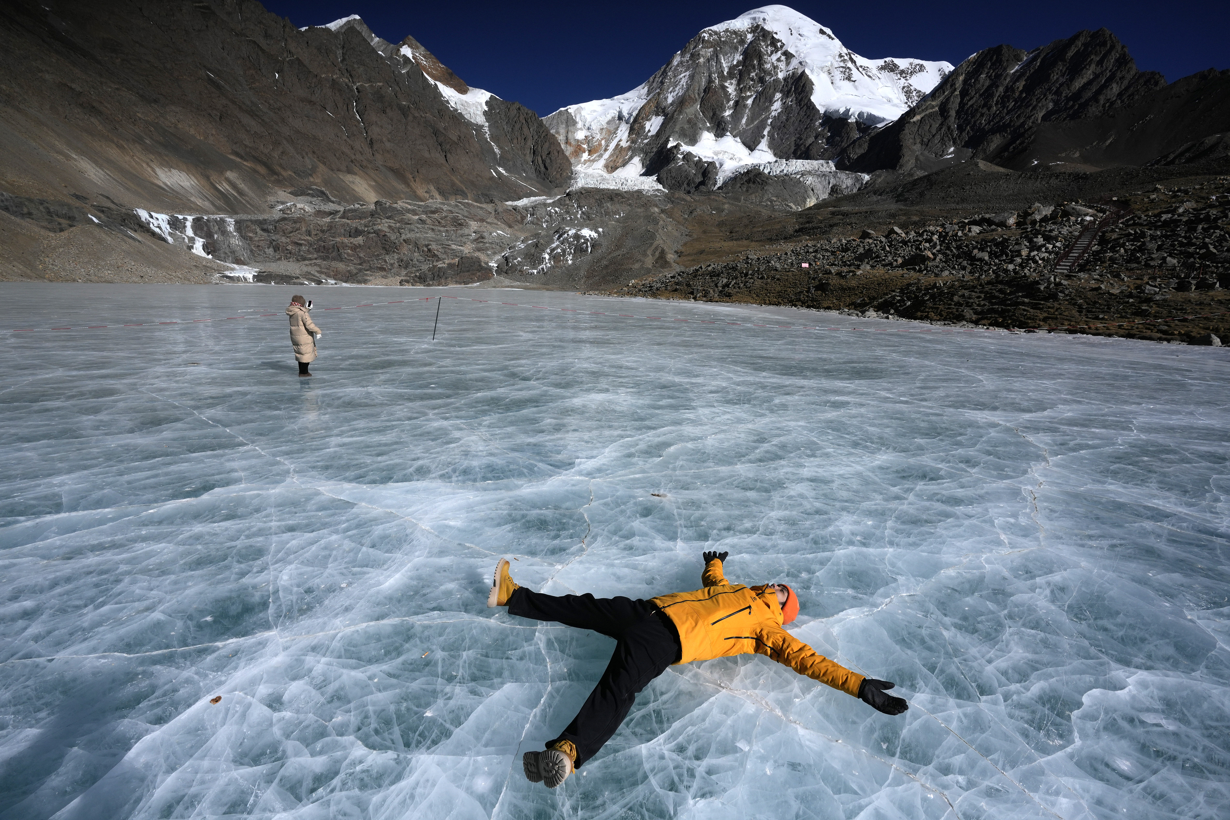 Visitors pose for photos on a frozen alpine lake at the foot of Qiongmu Gonga, a snow-capped mountain in Lhasa, Xizang Autonomous Region on January 16, 2025. /IC