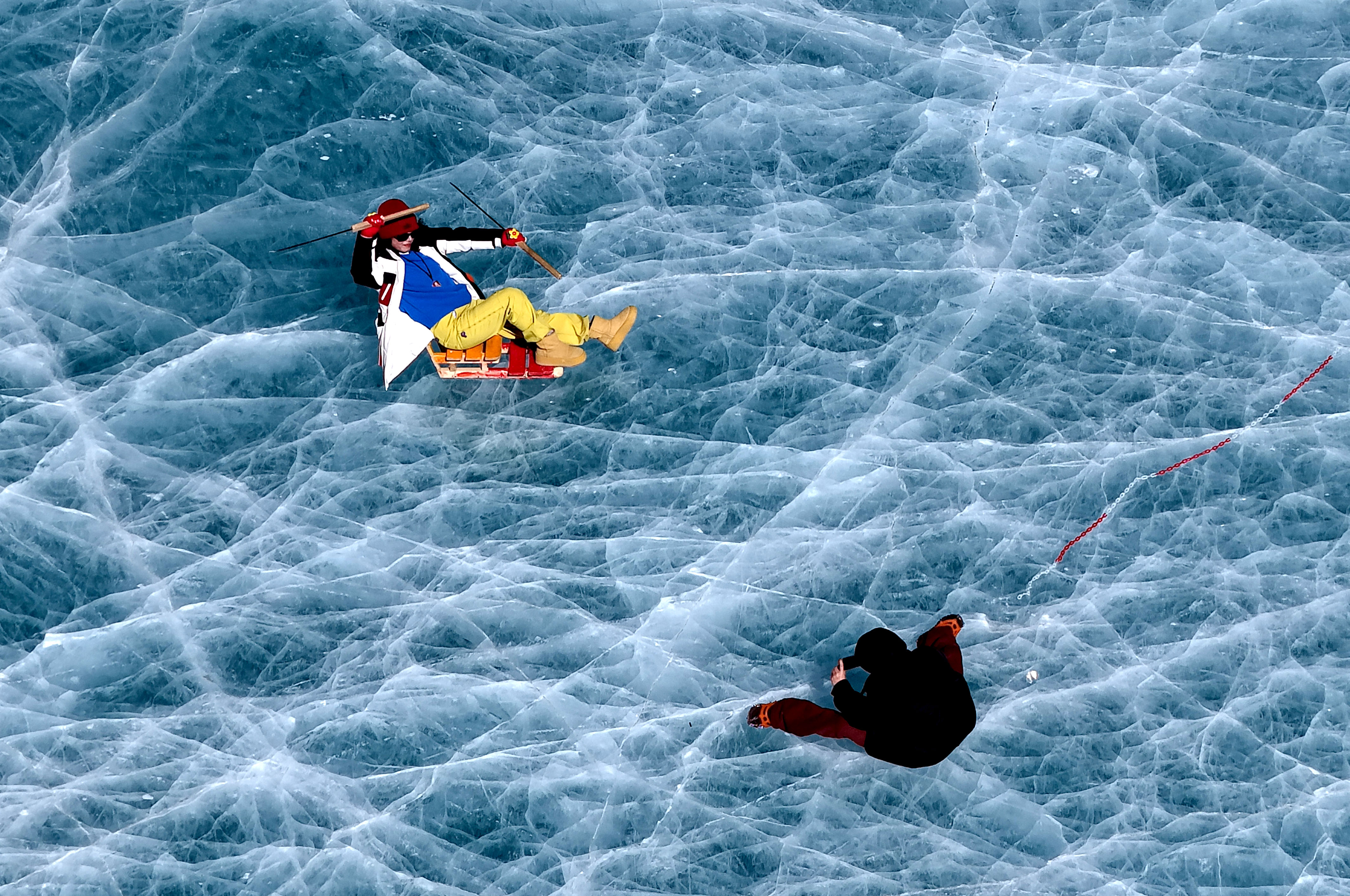 Visitors pose for photos on a frozen alpine lake at the foot of Qiongmu Gonga, a snow-capped mountain in Lhasa, Xizang Autonomous Region on January 16, 2025. /IC