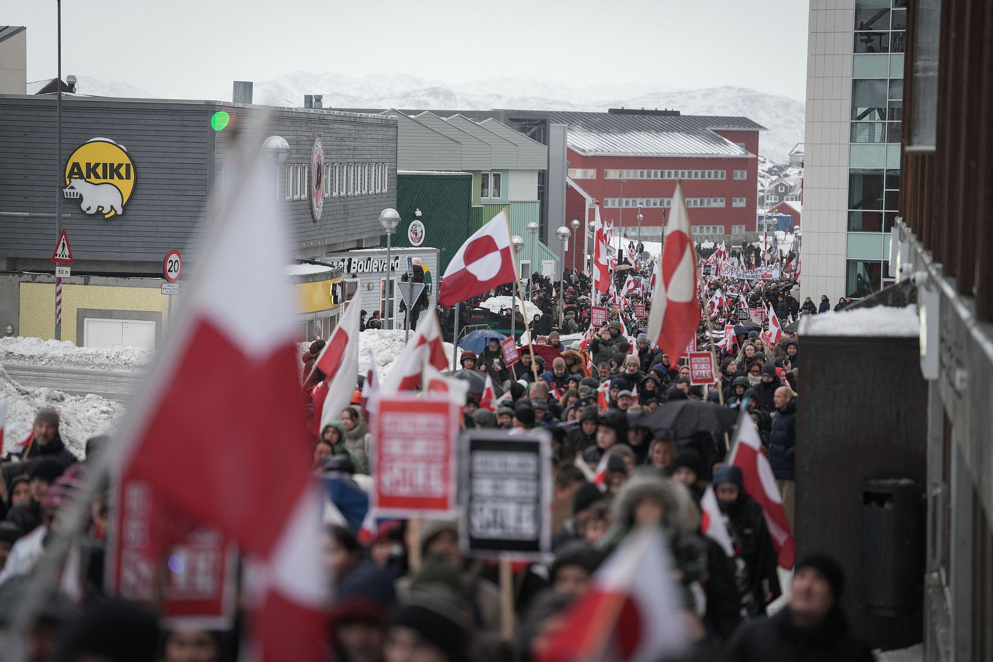 People wave Greenlandic flags as they take part in a demonstration that gathered almost a third of the city population to protest against the U.S. president's plans to 