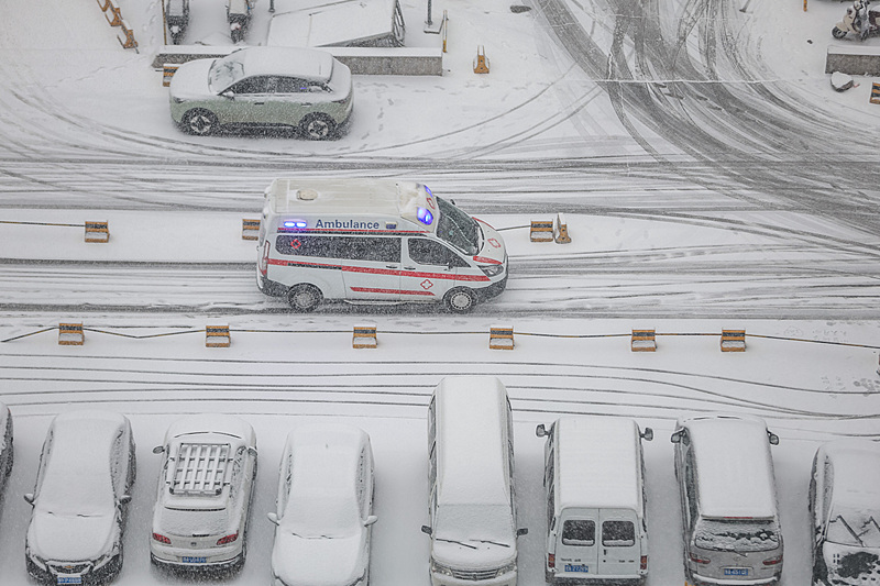 A medical ambulance drives through the snow in Zhengzhou, Henan Province, on January 19, 2026. /VCG