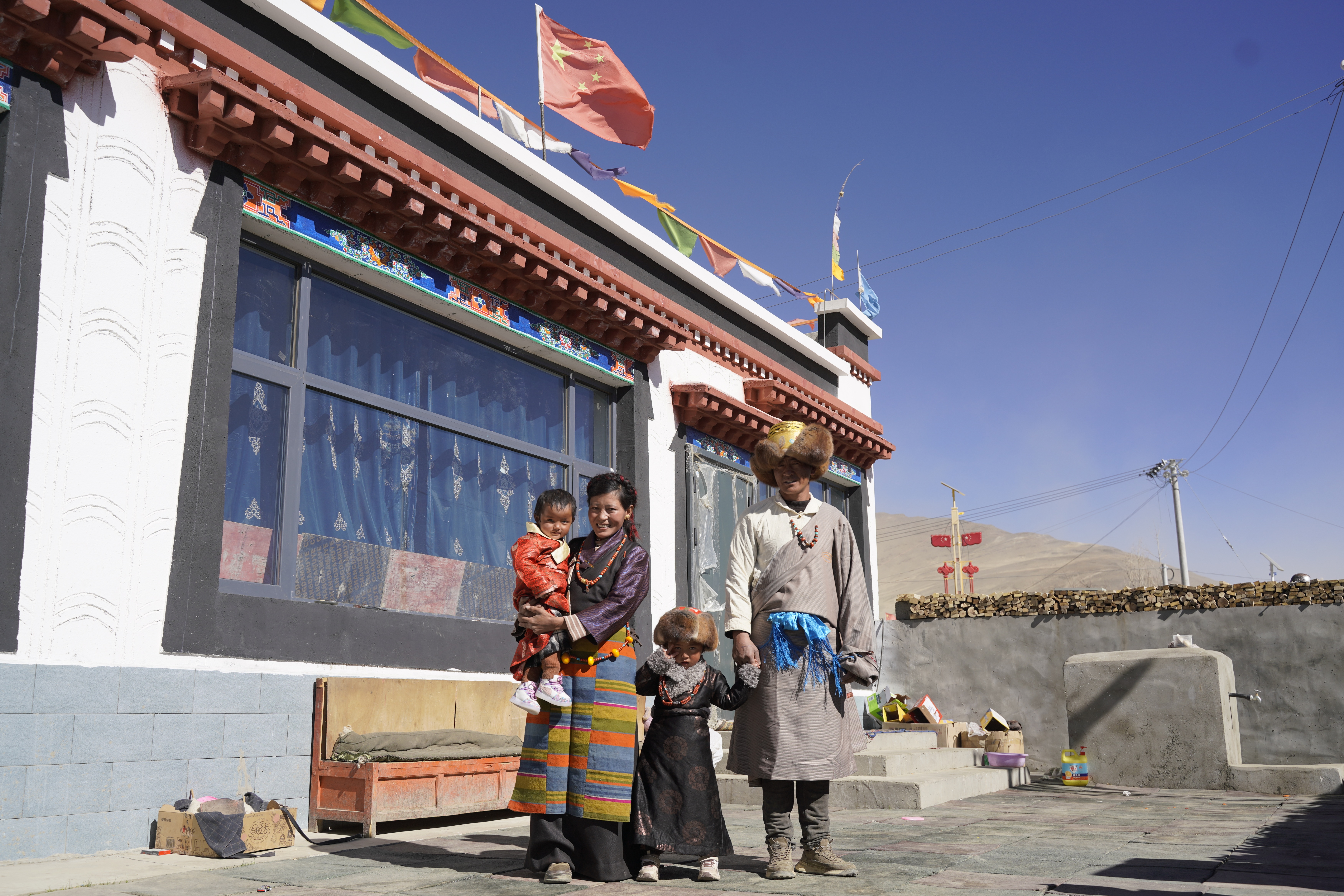 Dressed in local ethnic clothing, Tsewang Jamsan's family has their portrait taken in the courtyard of their new home in Xigaze, Xizang. /CMG