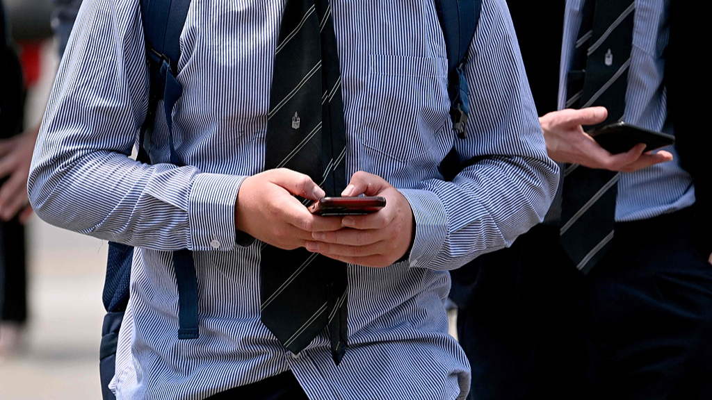 A schoolboy looks at smartphone in Melbourne, November 27, 2024. /VCG