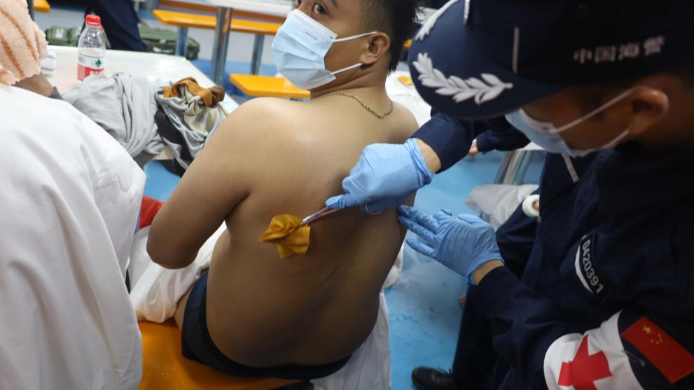 A rescued Filipino crew member is treated by a China Coast Guard member on January 23, 2026. /China Coast Guard