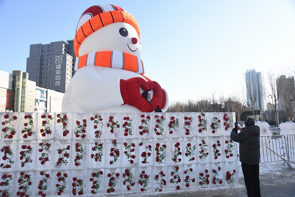 Flowers are seen frozen in an ice wall near a snowman display in Shenyang, Liaoning Province on January 22, 2026. /VCG