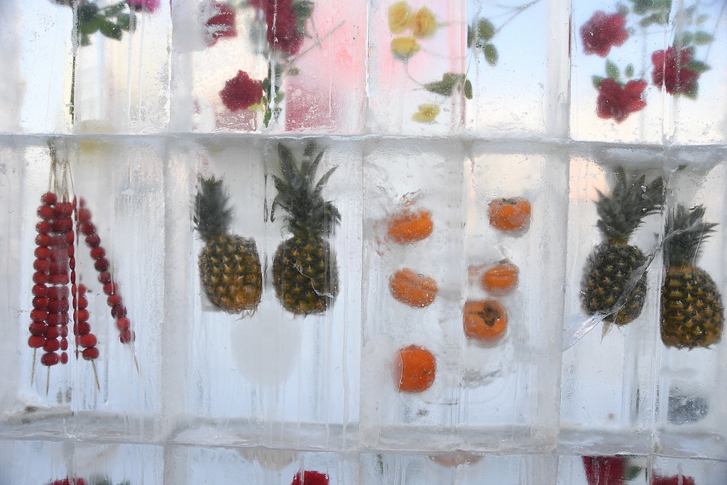Fruits and flowers are seen frozen in an ice wall near a snowman display in Shenyang, Liaoning Province on January 22, 2026. /VCG