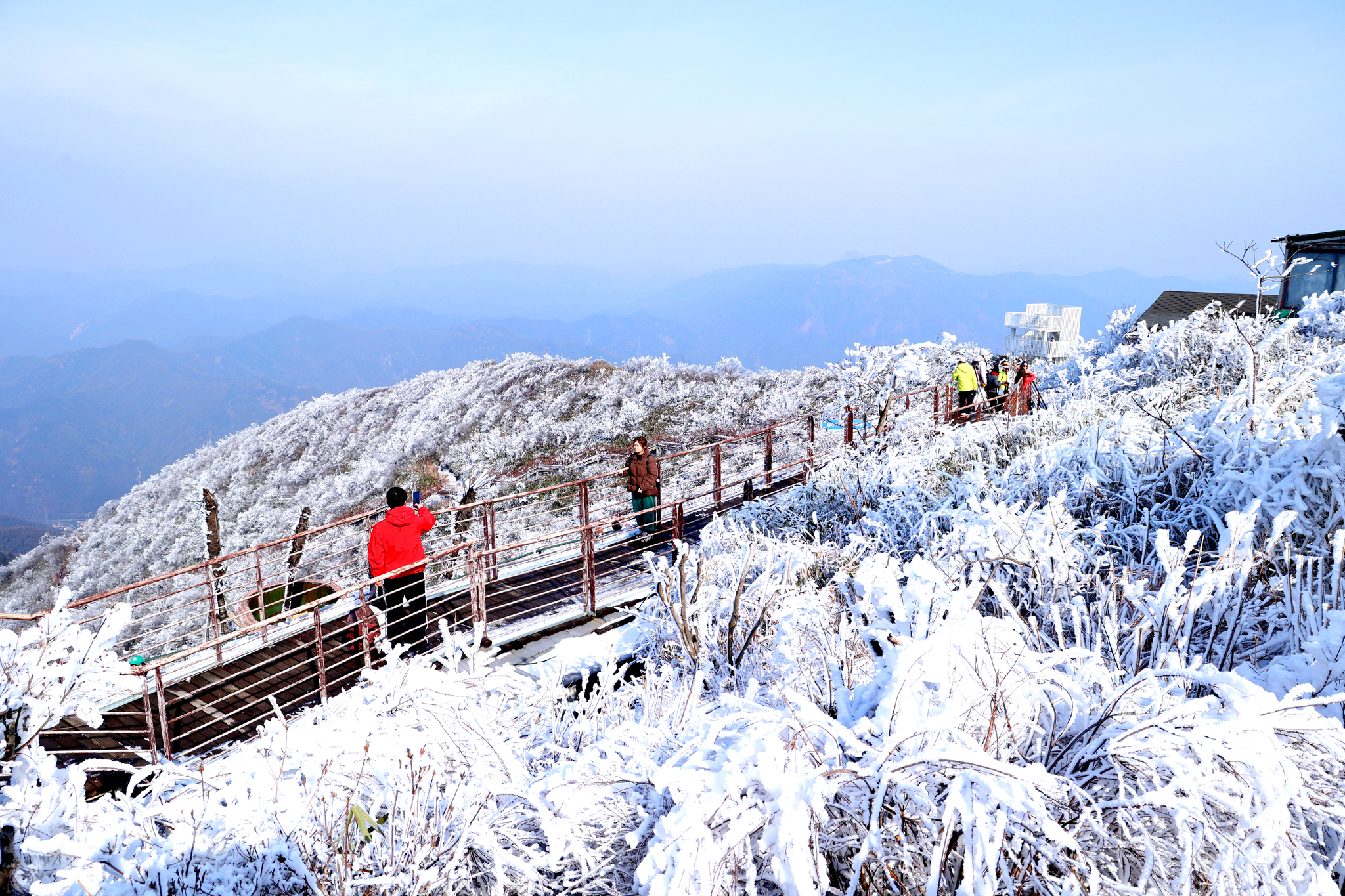 Visitors stop on a walkway of Luniao Mountain in Hangzhou, Zhejiang Province, to admire its stunning rime ice scenery on January 22, 2026. /VCG