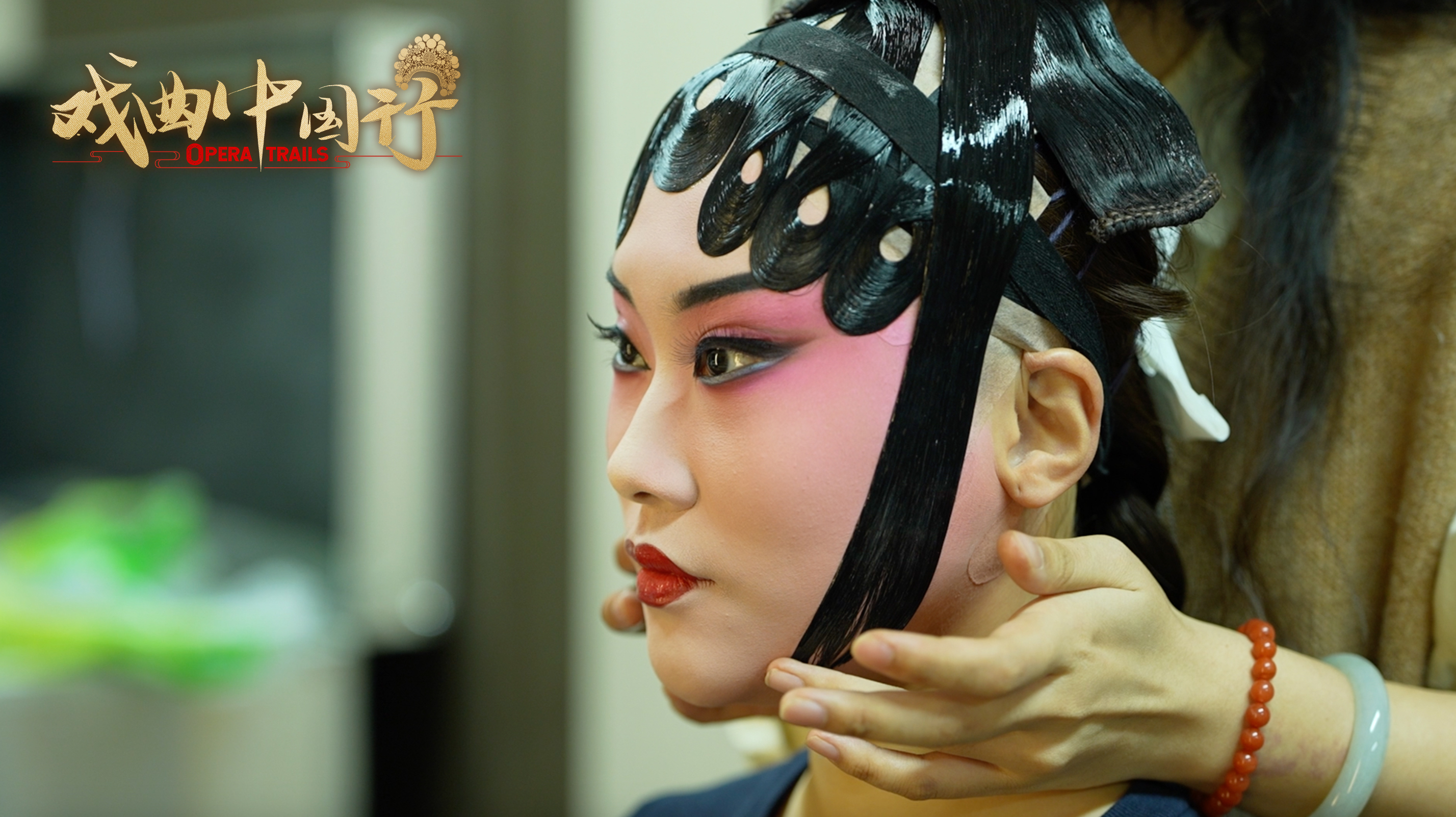 Traditional hair patches are applied to the performer's face as part of Pingju Opera makeup. /CGTN