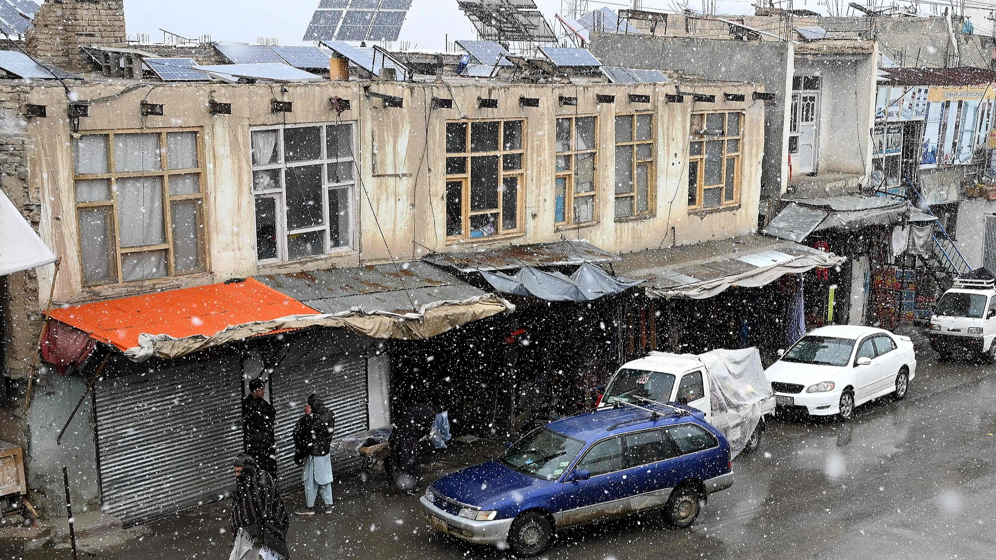 People walks at a street during snowfall at Siyagerd Bazaar in the Ghorband district of Afghanistan's Parwan province, January 21, 2026. /VCG