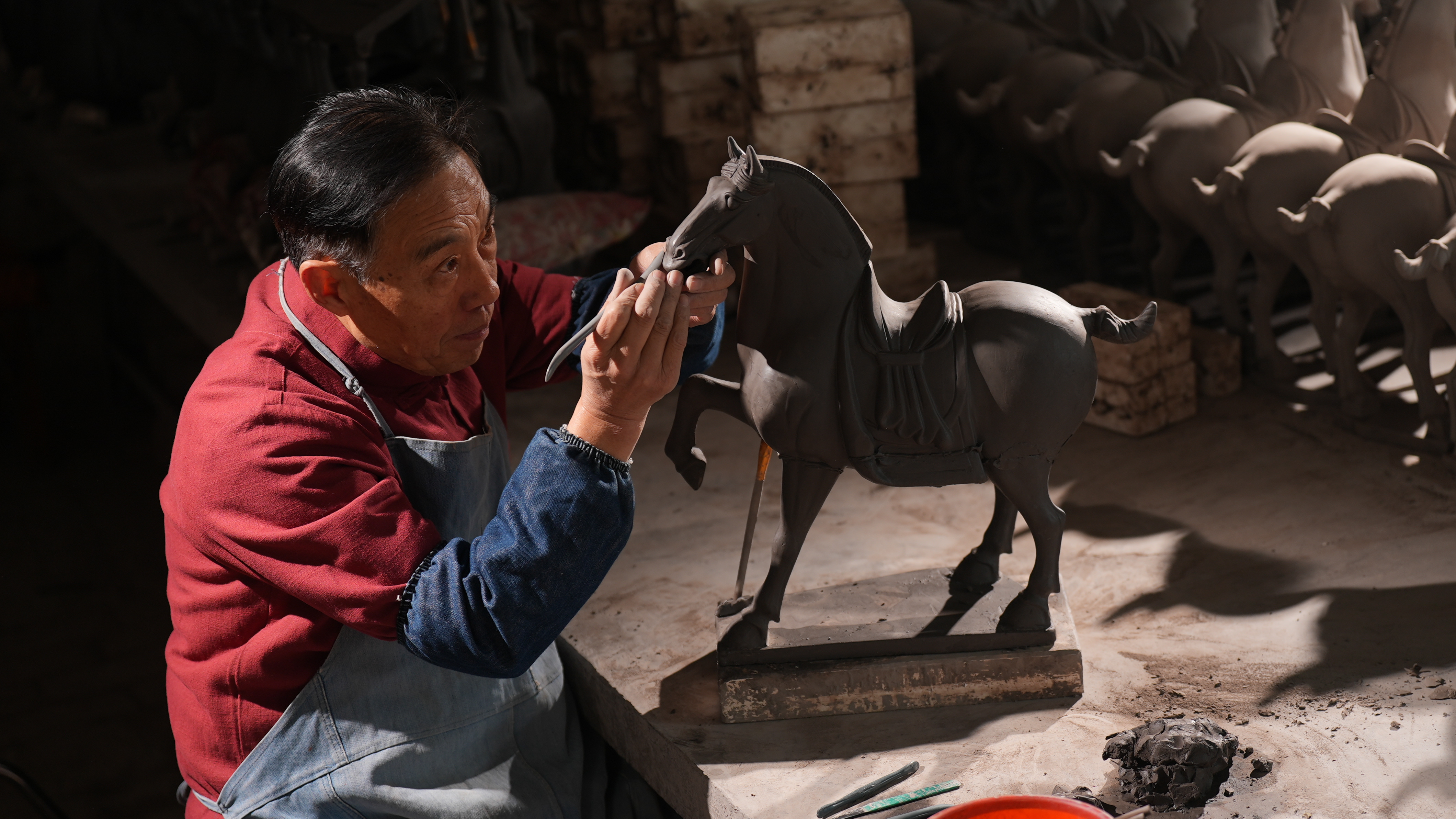 Gao Shuiwang carving the mold for a horse pottery. /CGTN