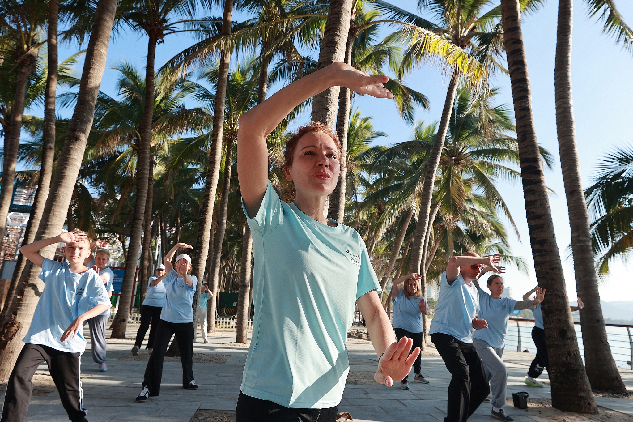 International students are practicing Tai Chi under the warm sun and shade of coconut trees at Dadonghai scenic area in Sanya, Hainan, January 9, 2026. /VCG