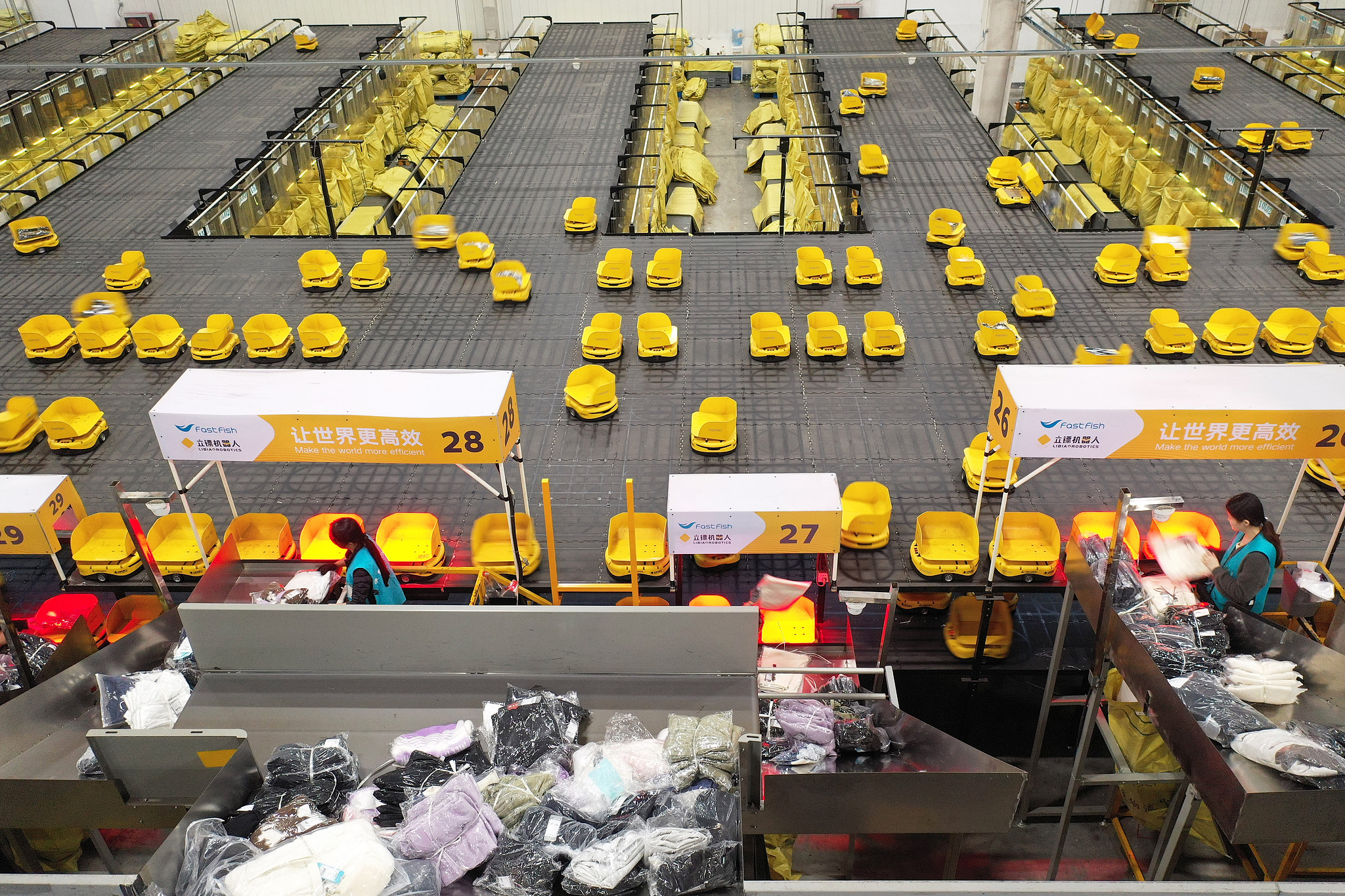 Workers assign apparel to sorting robots at the East China Logistics Center in Huzhou City, Zhejiang Province, on November 8, 2025. /VCG