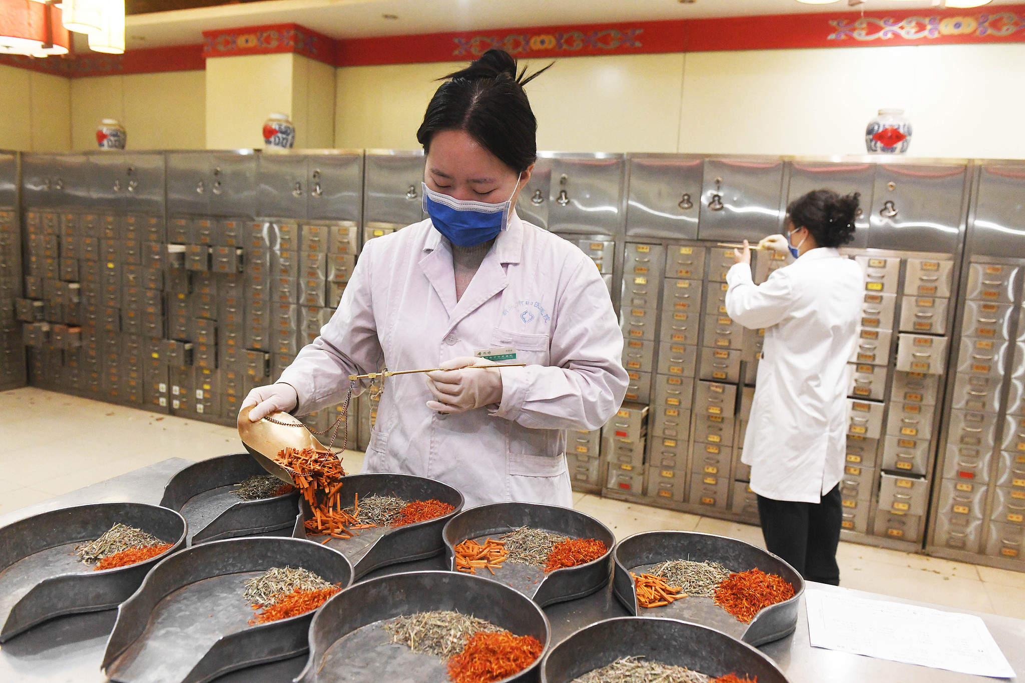 A pharmacist weighs and dispenses herbal medicine. /VCG