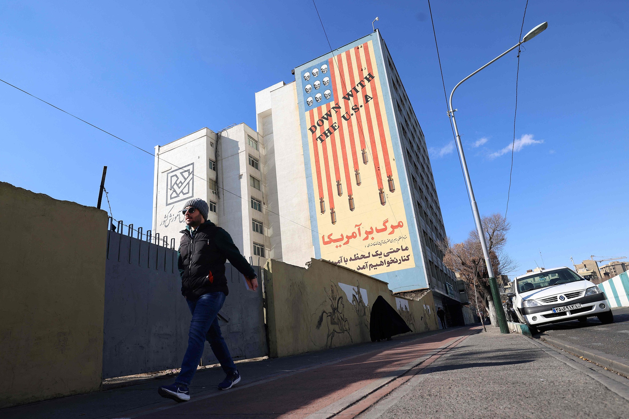 A man walks past a large anti-U.S. mural painted on the side of a building in Tehran, January 31, 2026. /VCG