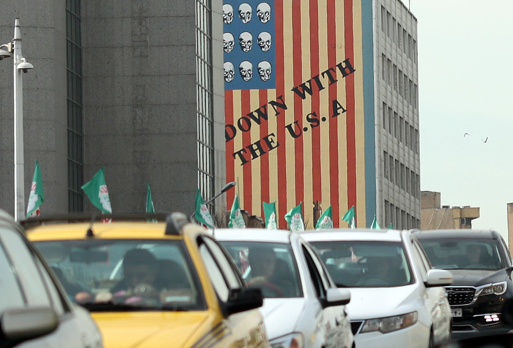 Iranians drive past next to an anti-U.S. mural in a street in Tehran, Iran, February 2, 2026. /VCG
