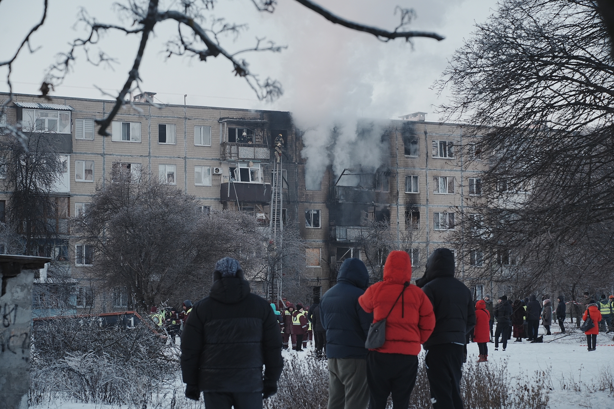 Residents wait in a yard while firefighters extinguish a fire in an apartment building damaged by a Russian drone on February 3, 2026 in Kharkiv, Ukraine. /VCG