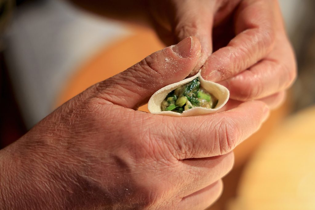 Families prepare dumplings together during New Year's Eve, a symbol of wealth and prosperity. /VCG