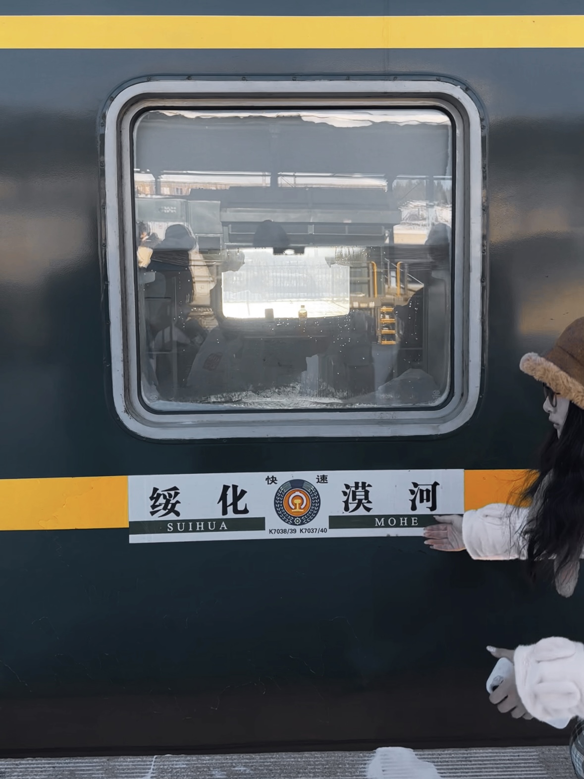 A traveler poses for photos near a train heading to Mohe at Suihua Railway Station in Heilongjiang Province. /CGTN