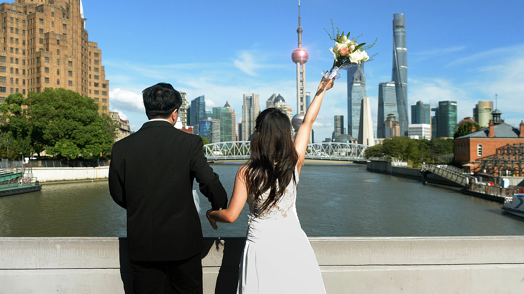 A newlywed couple poses for wedding photos along the Bund in Shanghai, August 29, 2025. /VCG