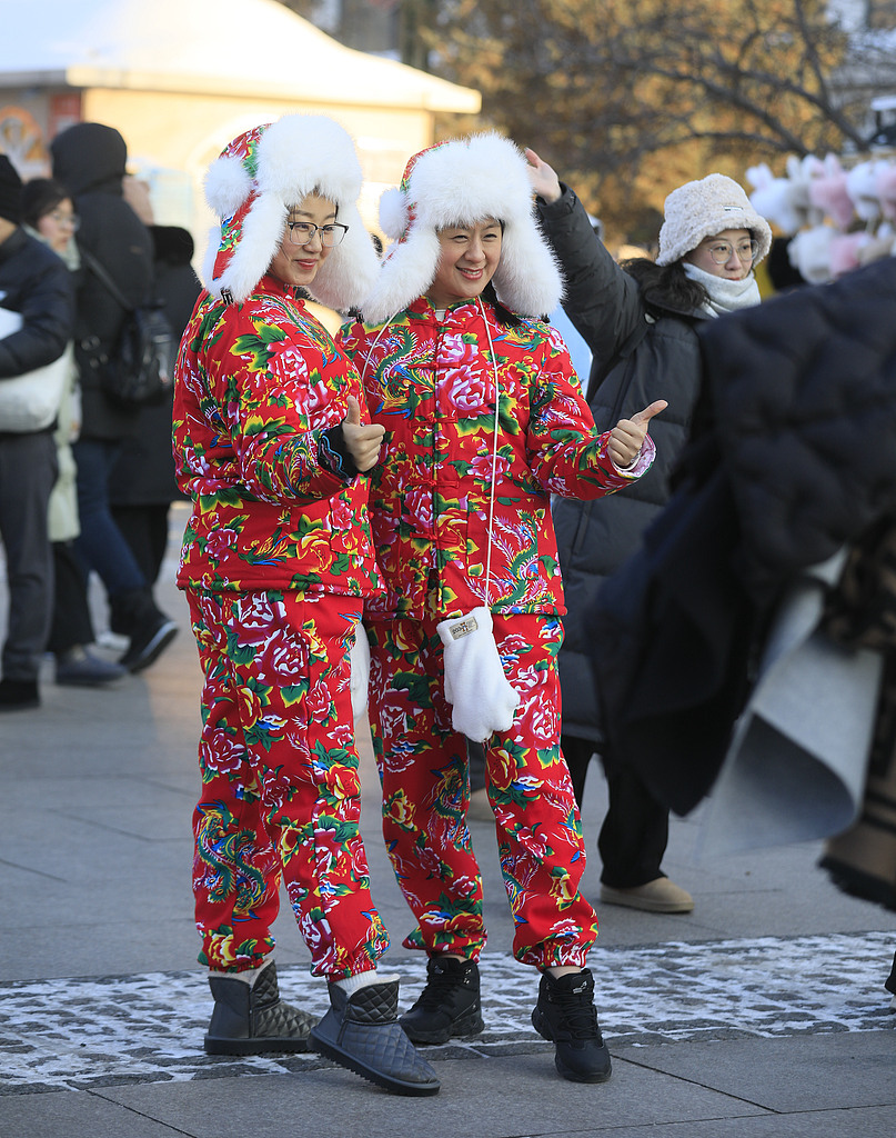 Two women wearing Dongbei floral patterned clothing pose for pictures in Harbin, Heilongjiang Province, in January 2024. /VCG 