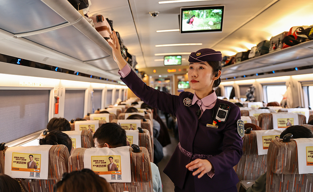 A railway staff member checks the luggage rack on a train in Shenyang, Liaoning Province, on February 1, 2025. /VCG