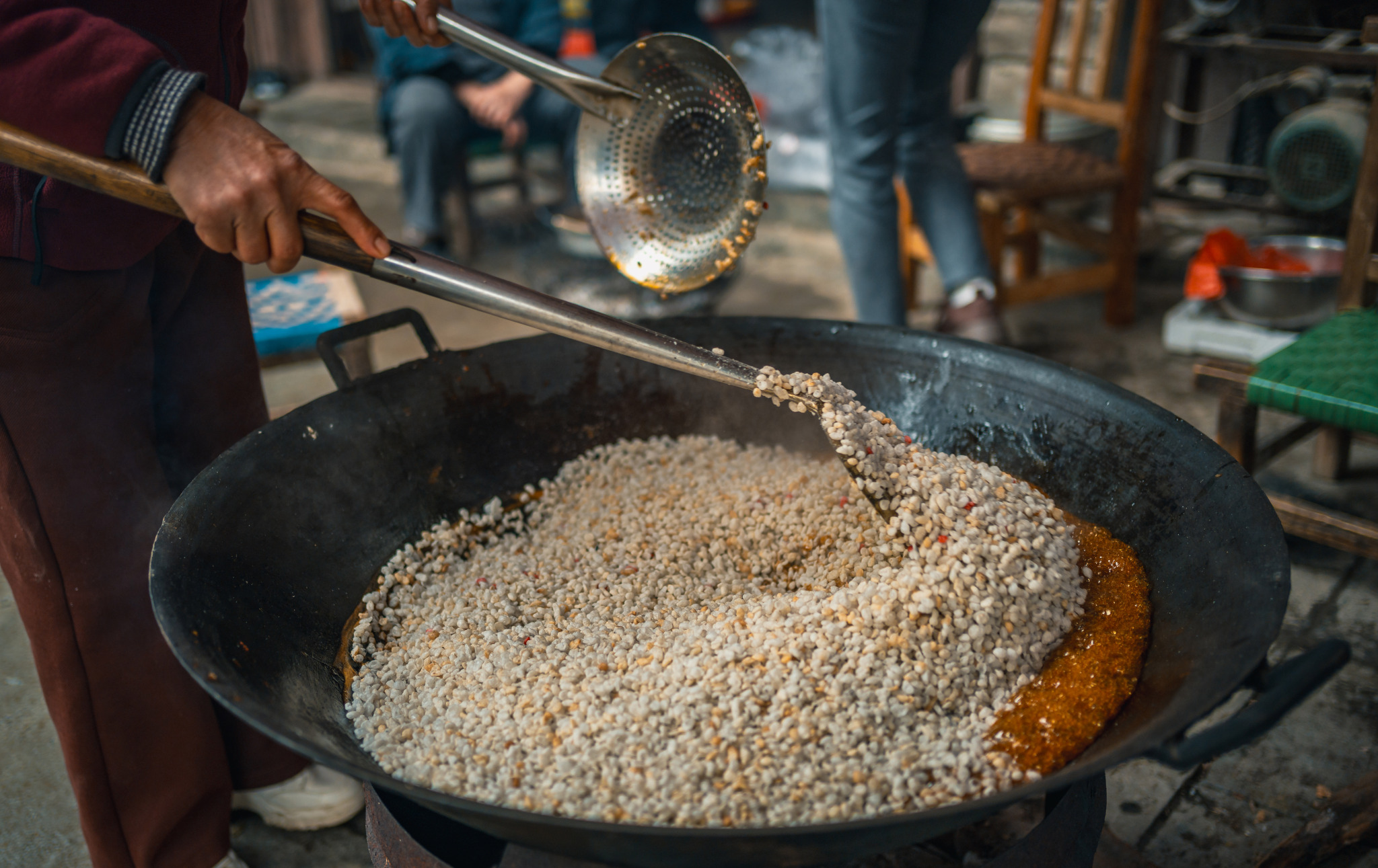 Puffed rice is mixed into brown sugar syrup as locals make brown sugar rice puffs in Wangmo County, Guizhou Province on February 12, 2026. /VCG