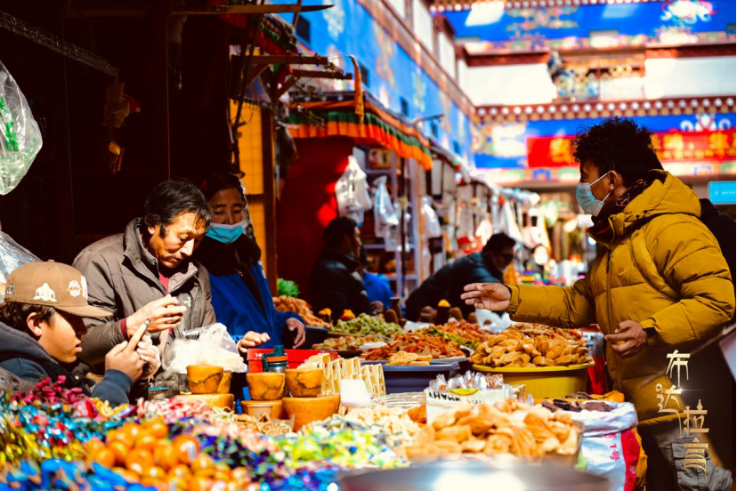 A shopper buys kasai, a traditional festive pastry, at the Tibetan New Year market in Barkhor Old Town in Lhasa, southwest China's Xizang Autonomous Region. /CGTN