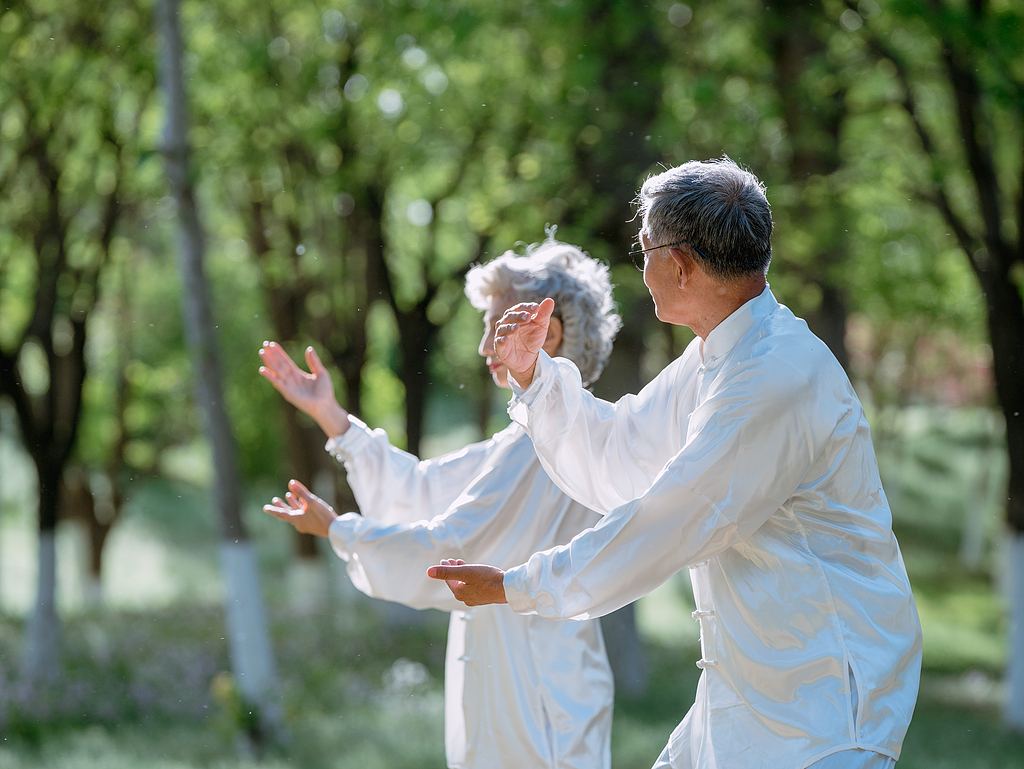 People practice tai chi in the park. /VCG